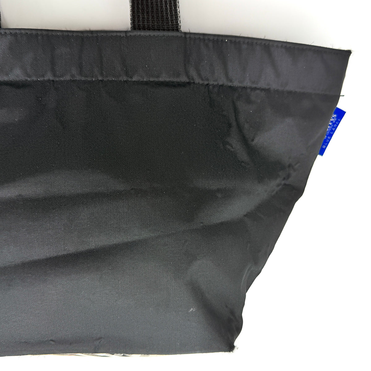Burberry Blue Label Nova Check tote bag in black nylon with beige checked base and webbed handles, shown on white background.