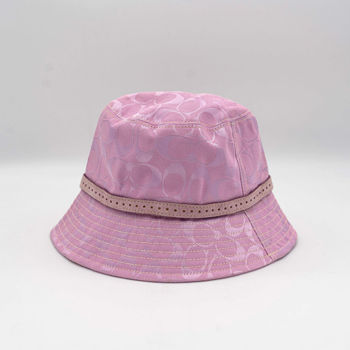 Coach pink jacquard bucket hat with taupe suede-effect band, shown against a neutral background.