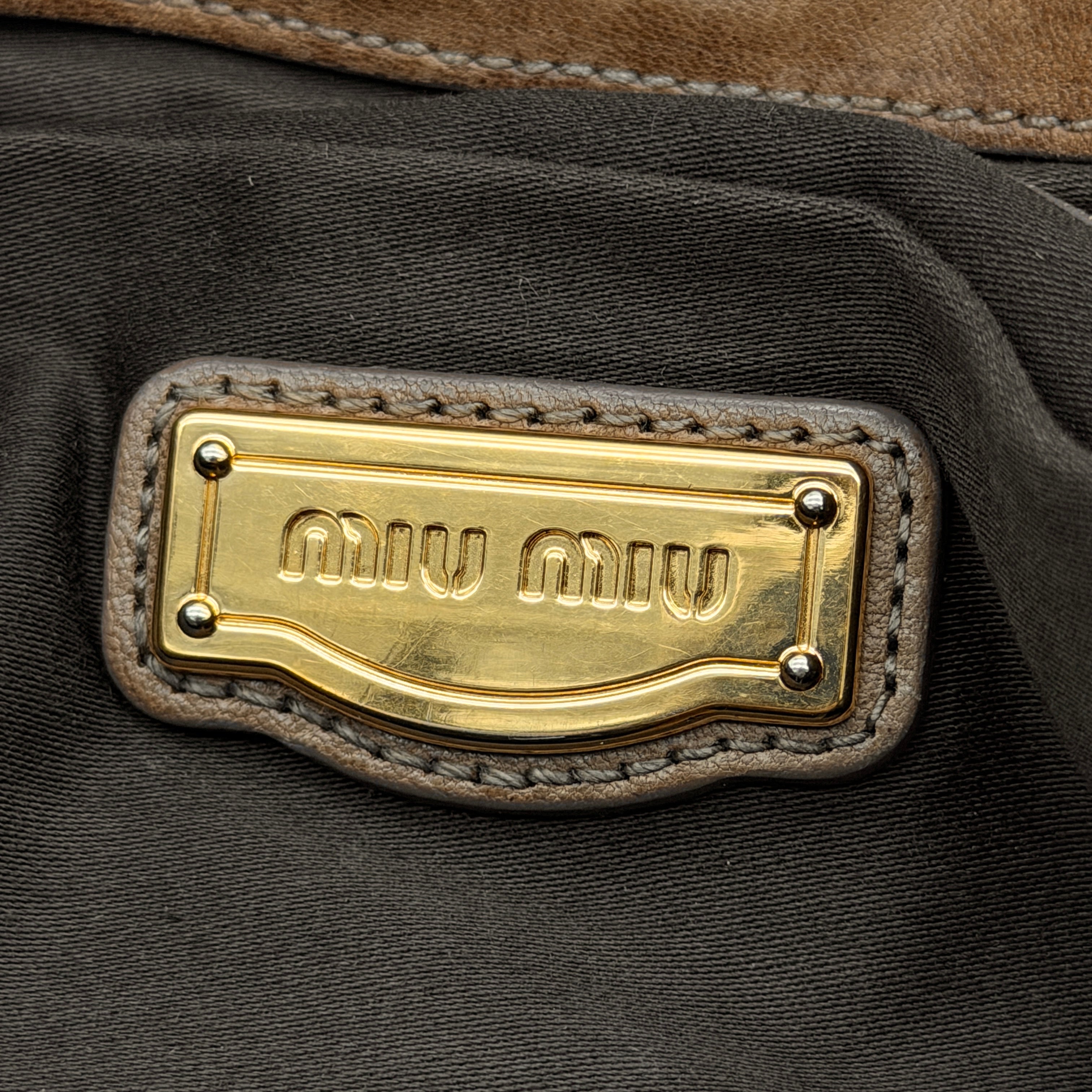 Miu Miu brown Matelasse Coffer Hobo bag with gold hardware, detachable strap, and dust bag displayed on a flat surface.