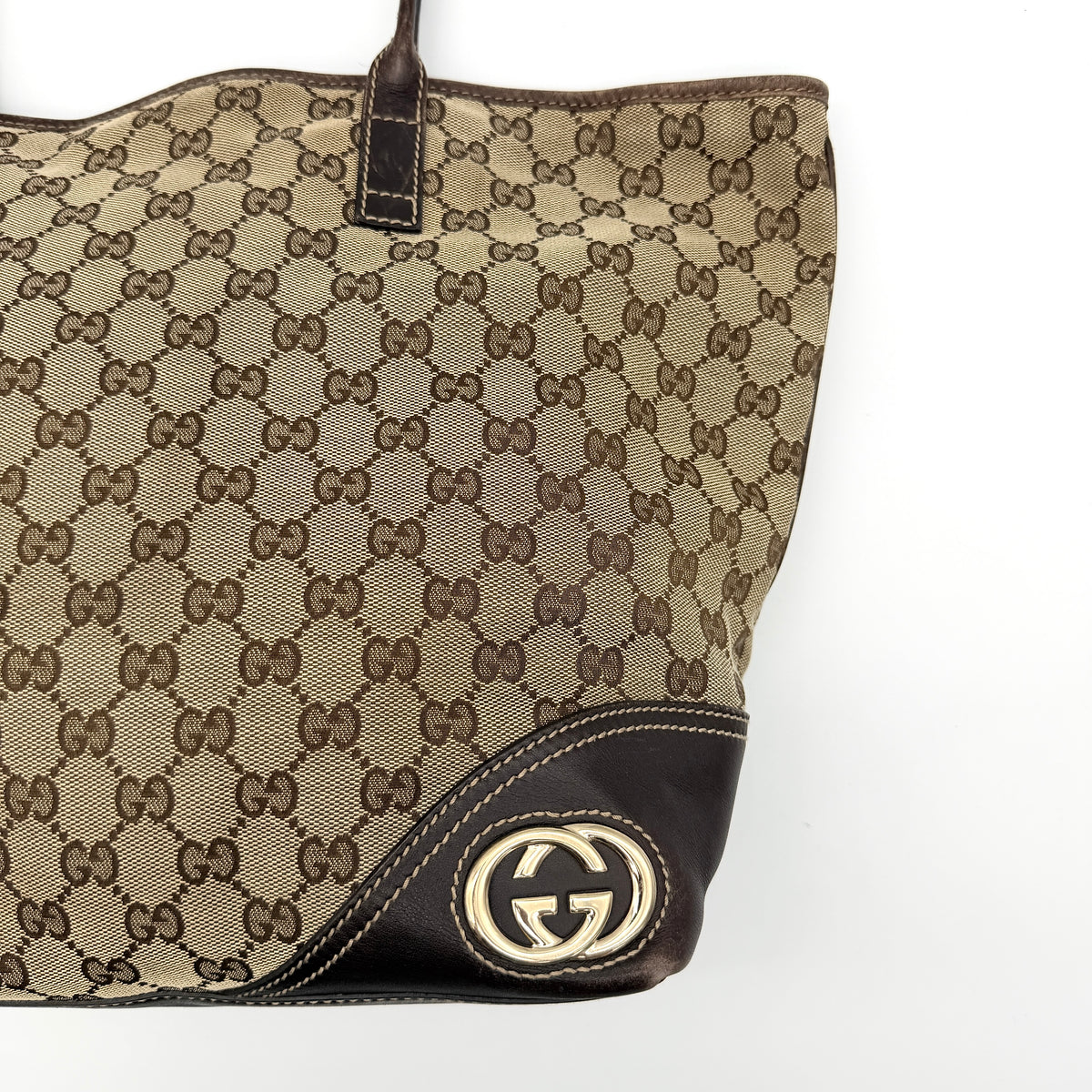 Gucci GG Monogram New Britt Tote Bag in beige and brown canvas with leather trim and gold-tone logo, presented against a white backdrop.