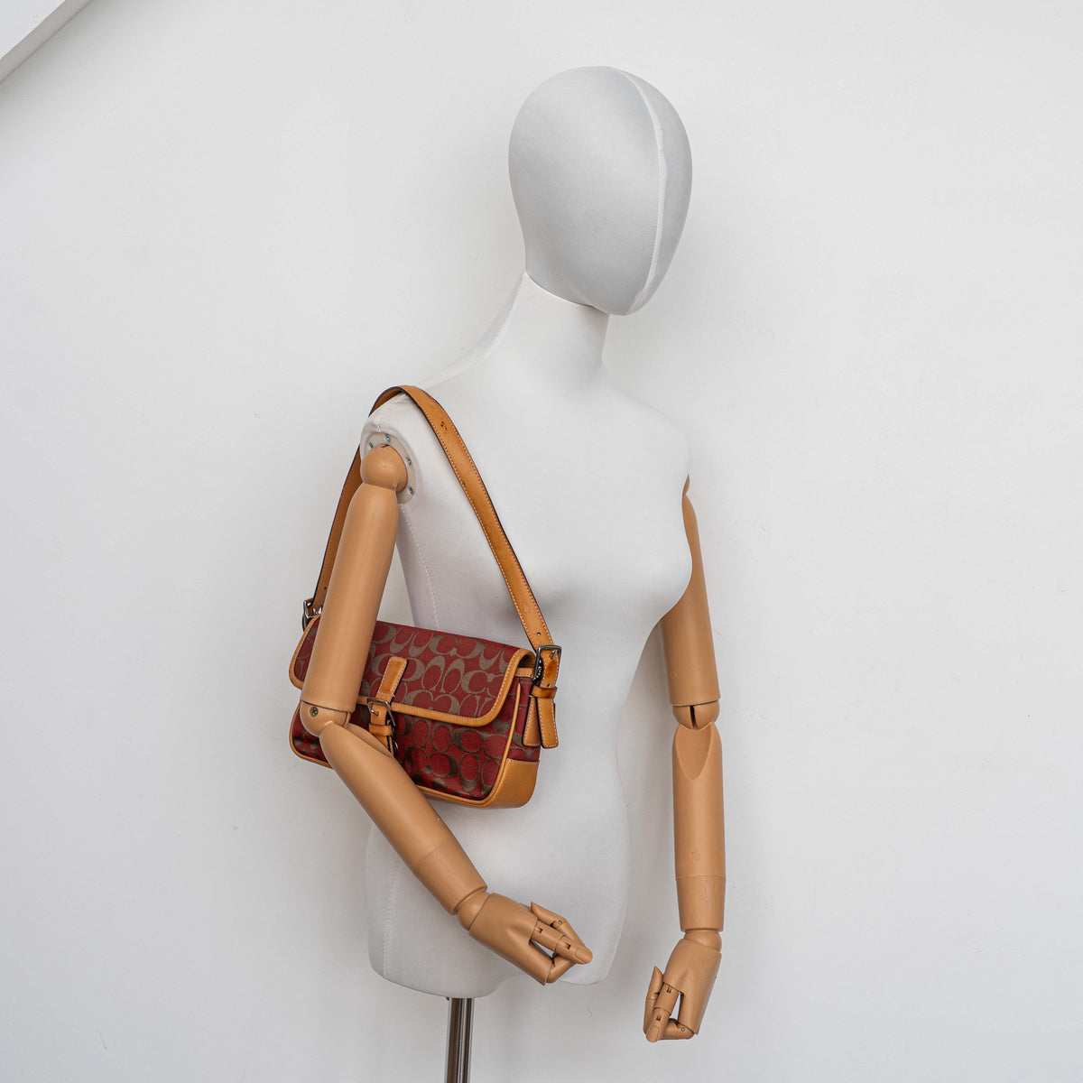 Coach Signature Soho Buckle Baguette in red and tan canvas with leather trim and a silver buckle, shown on a white background.