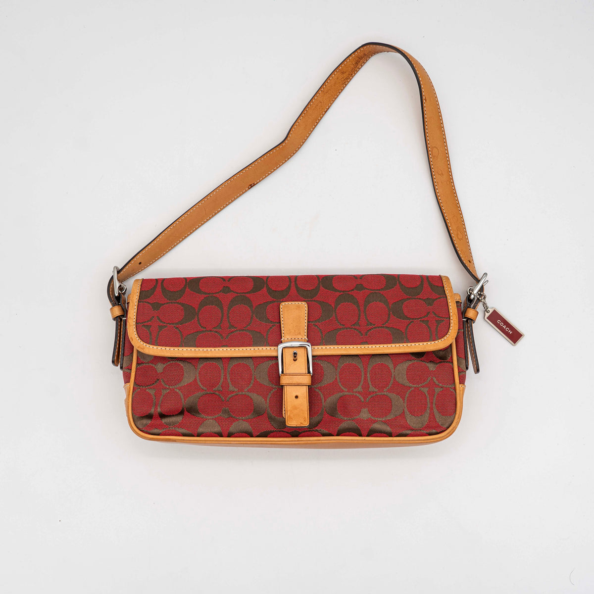 Coach Signature Soho Buckle Baguette in red and tan canvas with leather trim and a silver buckle, shown on a white background.