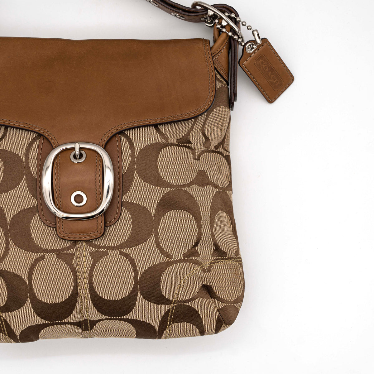 Coach 2Way Signature Soho Buckle Flap Shoulder Bag in beige and tan with silver buckle and adjustable leather strap, shown on a white background.