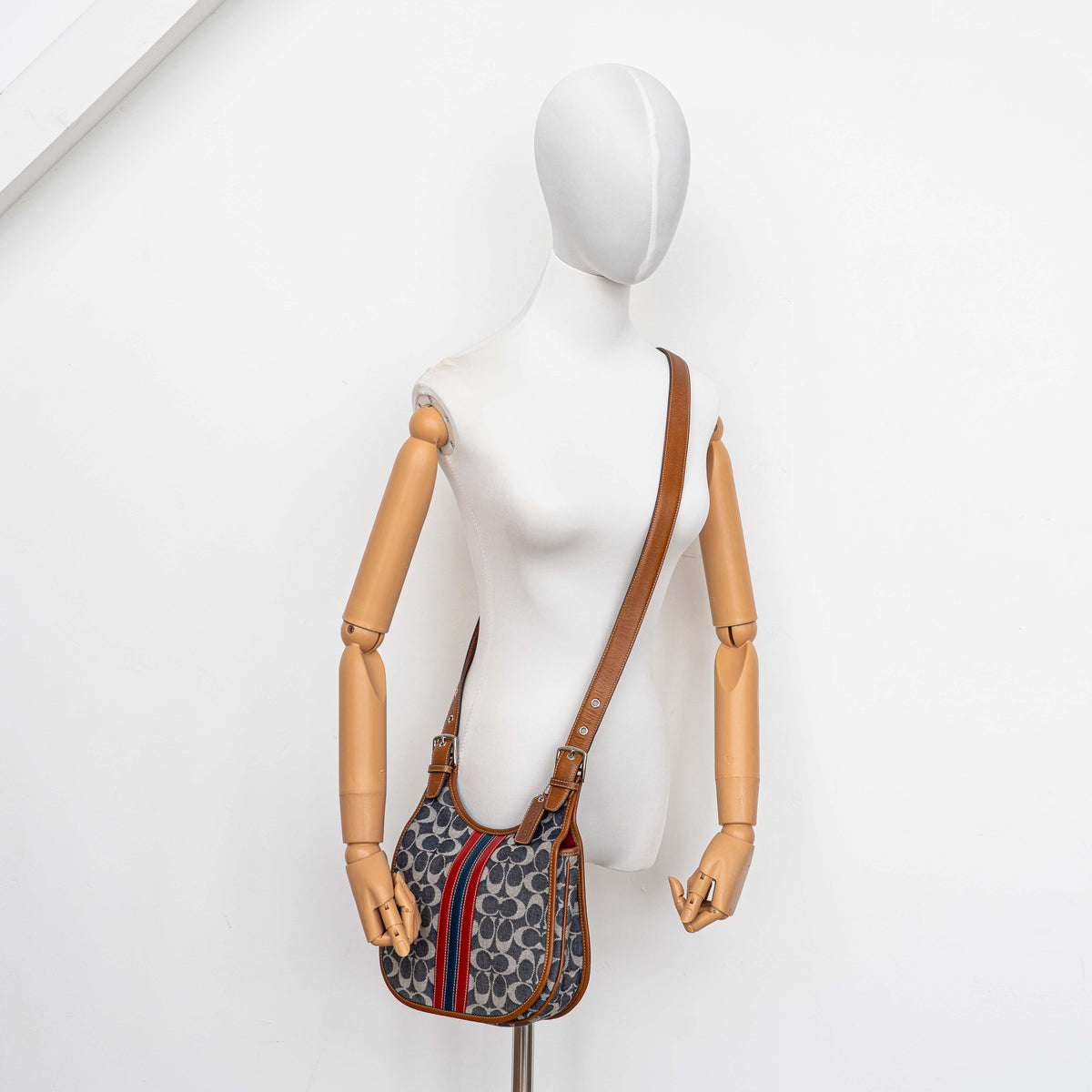 Coach signature denim hobo crossbody bag with red and blue stripe, brown leather trim, and an adjustable strap.