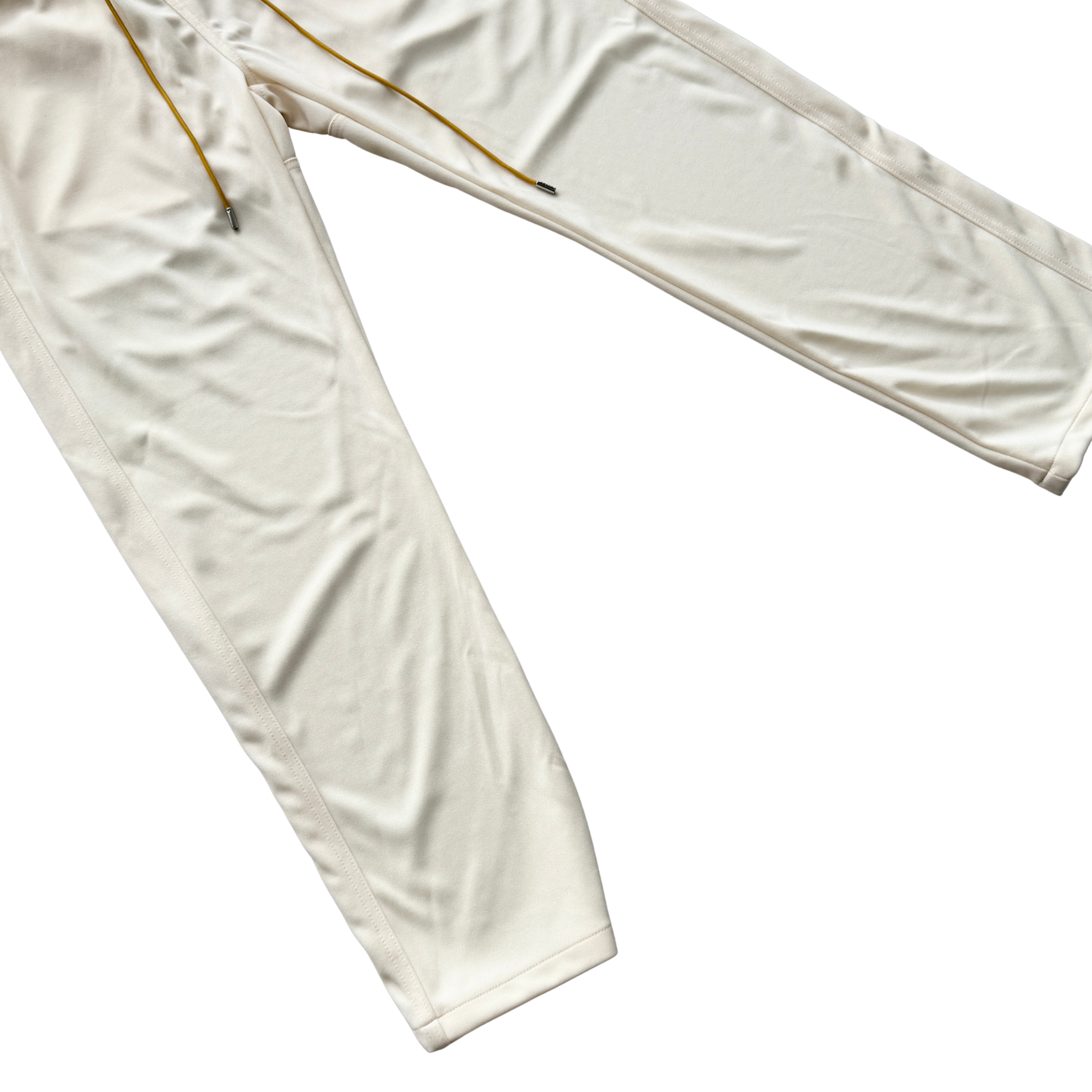 Rhude lounge track pants in cream with yellow drawstrings, displayed flat against a white background.