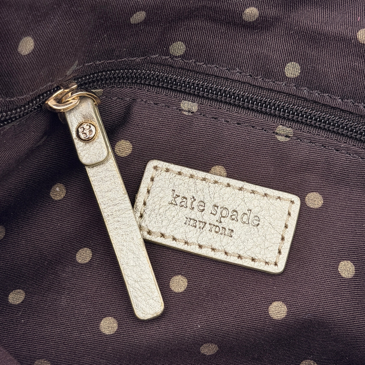 Navy blue suede Kate Spade baguette bag with floral gold hardware and gold-tone shoulder strap.