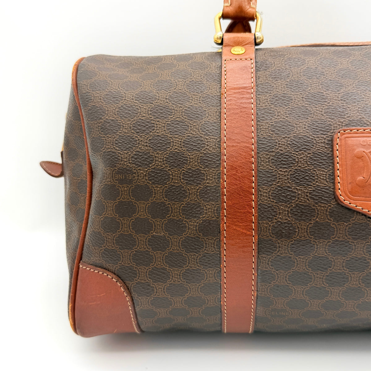 Celine Macadam Triomphe Boston Bag in brown coated canvas with tan leather and gold-tone hardware, shown against a white background.