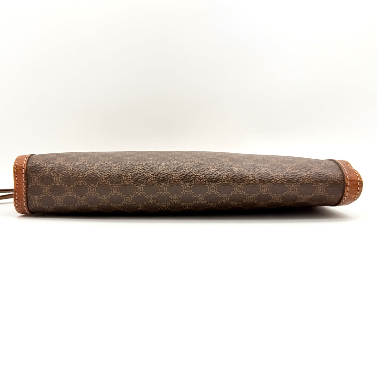 Celine Triomphe Macadam clutch bag in brown canvas with tan leather trim and gold hardware, shown with wrist strap.