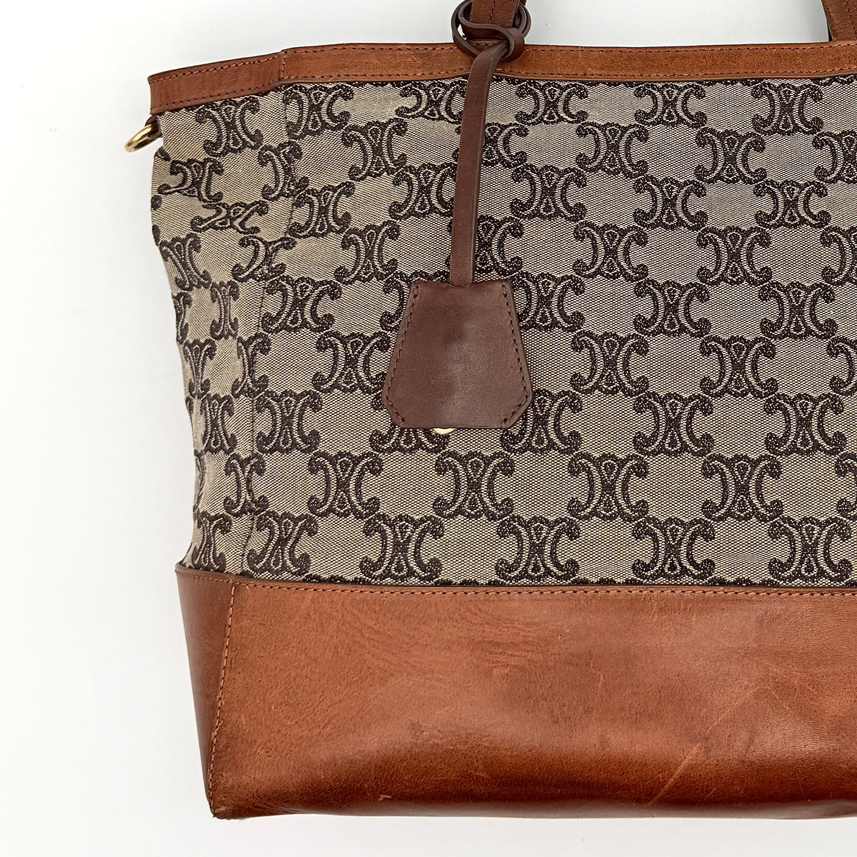 Celine Triomphe Macadam Canvas Tote Bag in beige and brown with leather trim and top handles, styled against a white background.