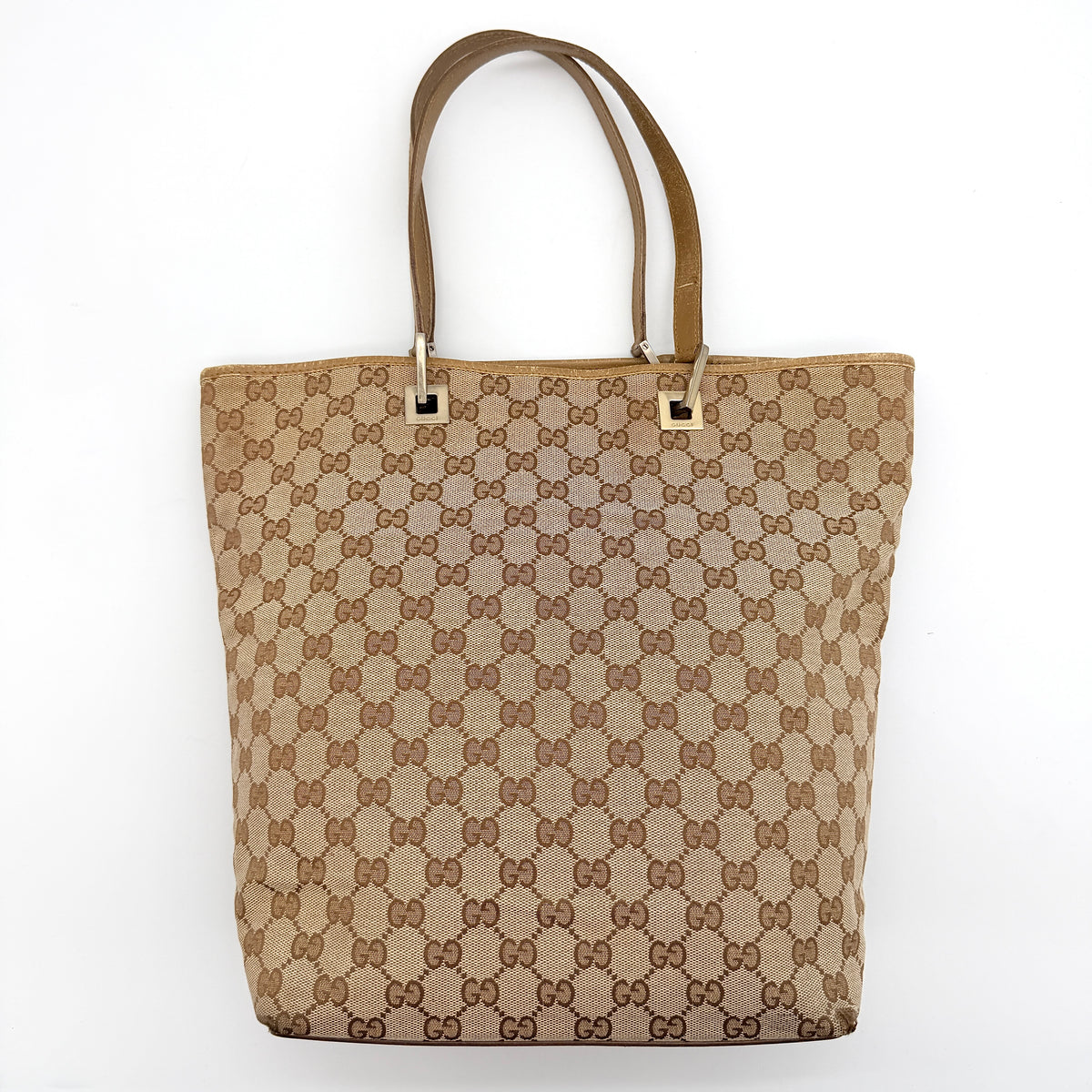 Front-facing Gucci GG Monogram Tote Bag in beige canvas with brown leather trim and double handles.