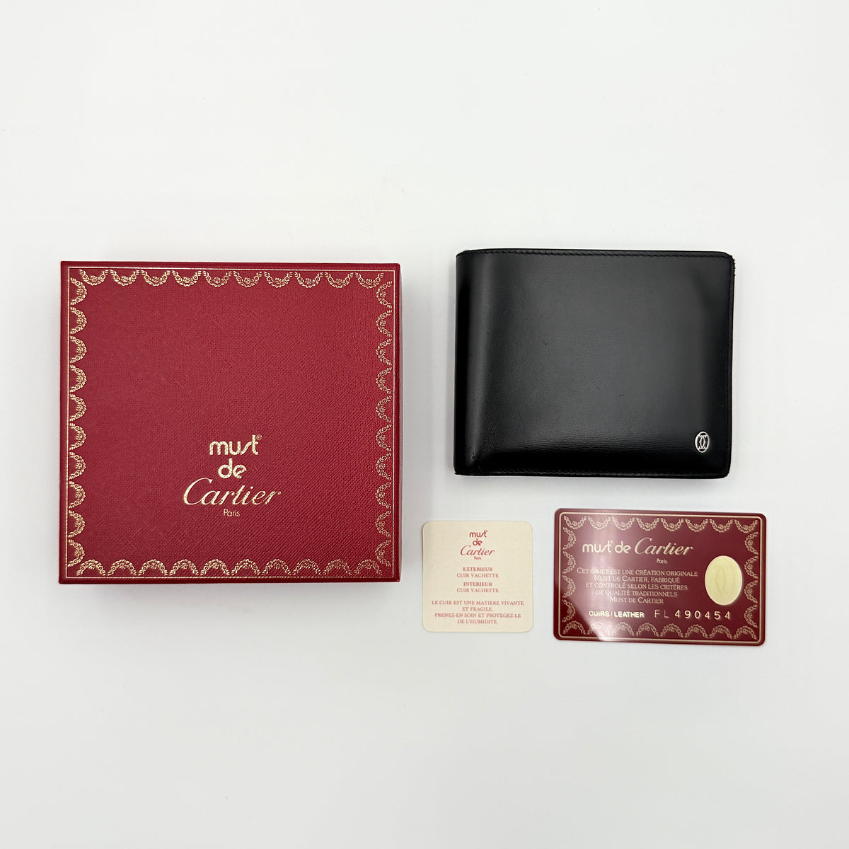 Cartier Must de Cartier black leather bifold wallet, shown with its signature red box and authentication card.