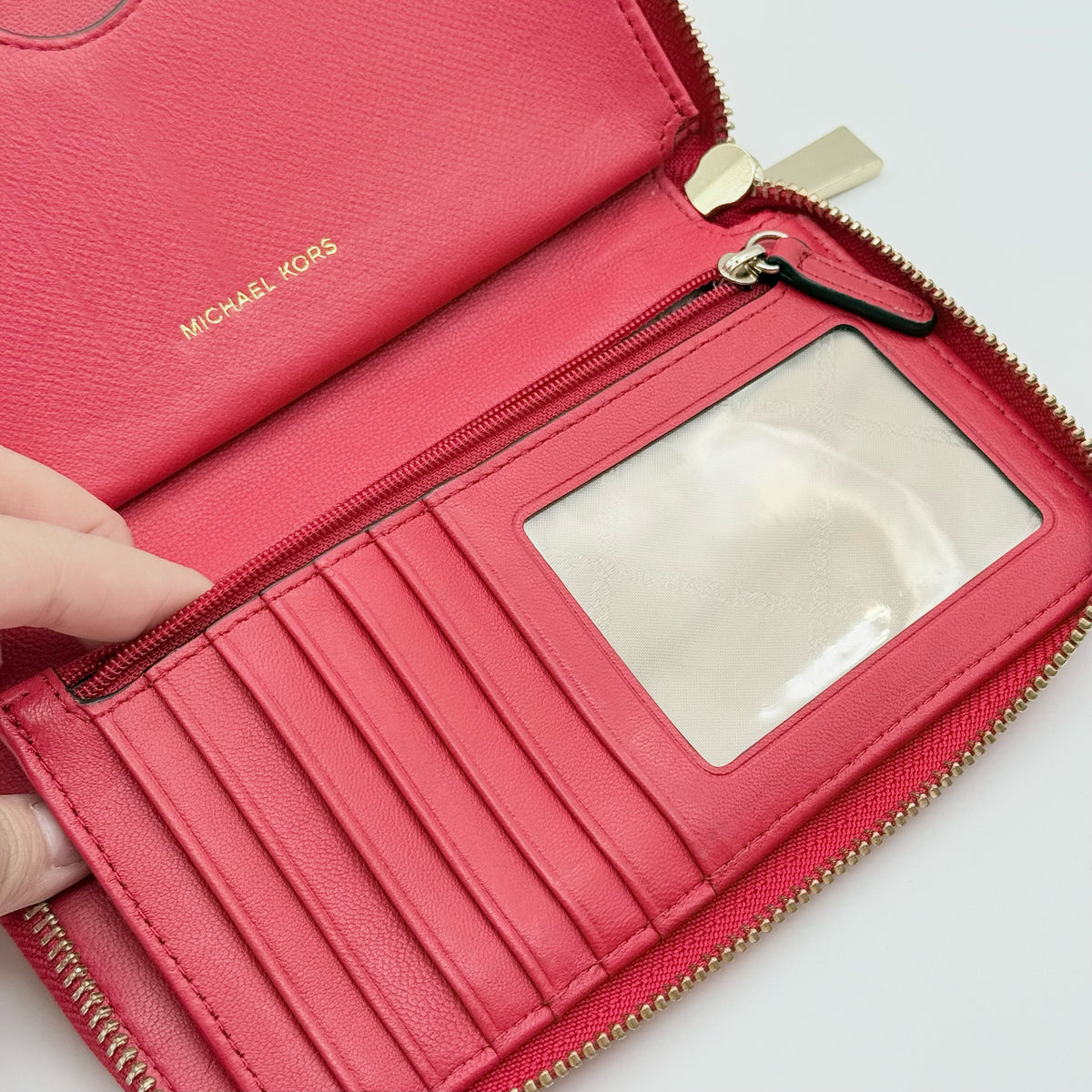Front view of the Michael Kors red quilted large wallet with gold zip and MK monogram stitching.