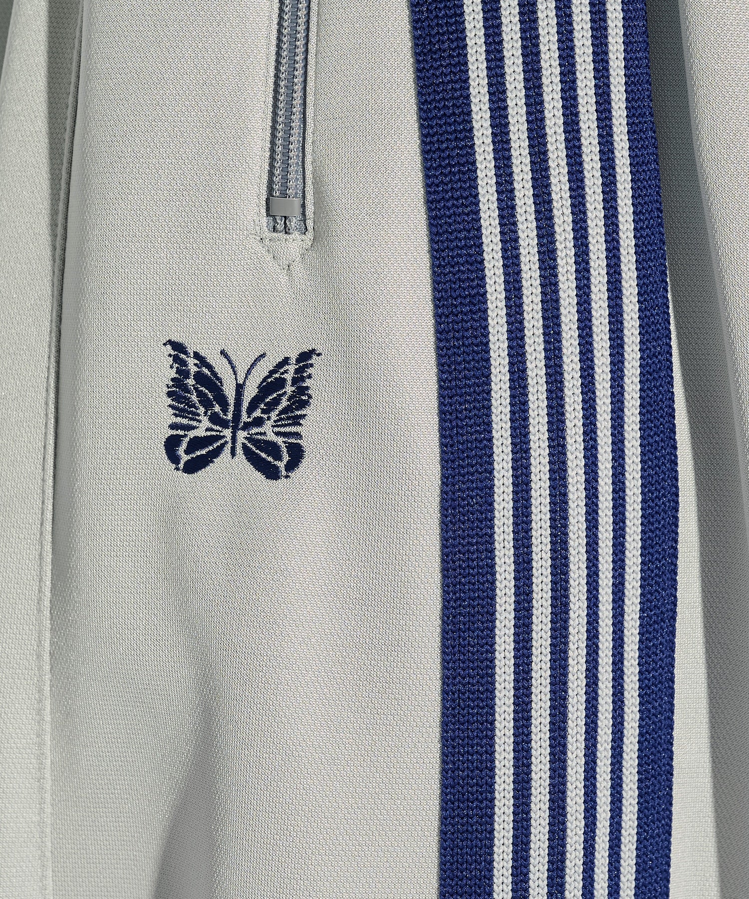 Grey Needles H.D. Track Pant with blue side stripes and butterfly logo, shown from a side angle.