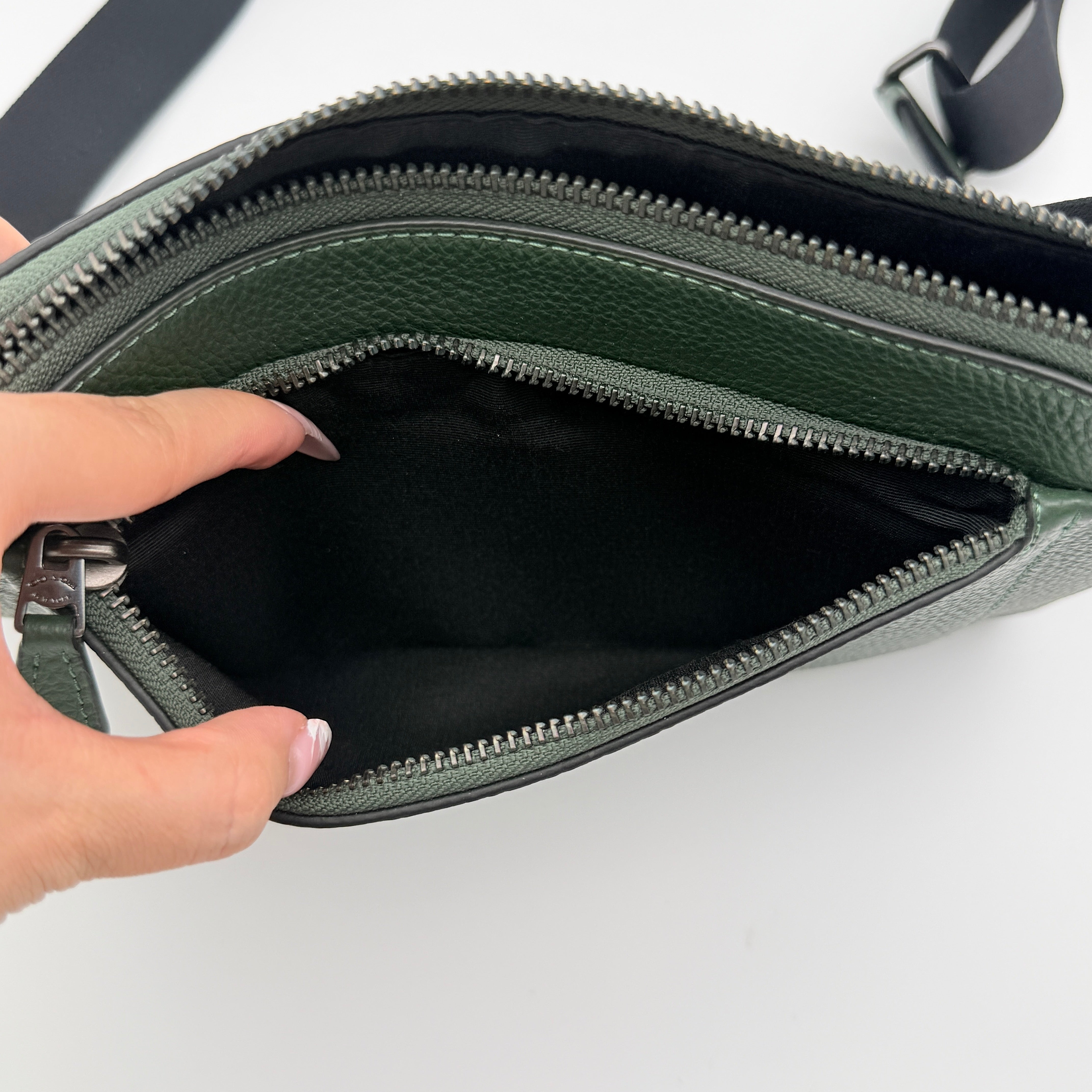 Coach Holden Crossbody bag in dark green pebbled leather with adjustable black webbing strap, displayed against a white background.