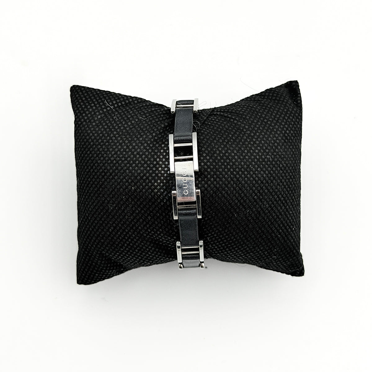 Gucci 3900L black dial watch with silver-tone rectangular case and black leather strap displayed on a stand