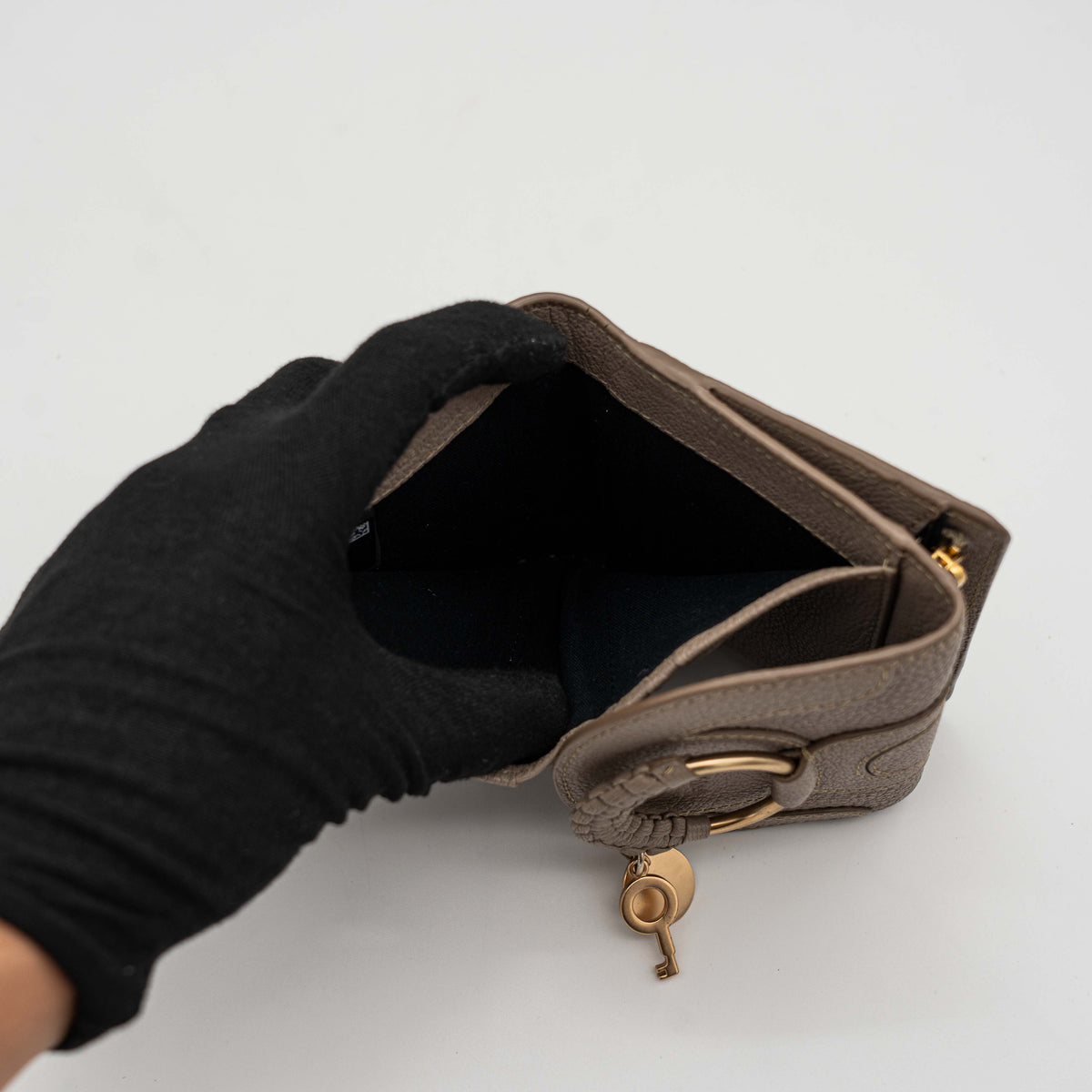 See by Chloe Hana tri-fold wallet in grey grained leather with gold-tone ring and charms, photographed closed on a white background.