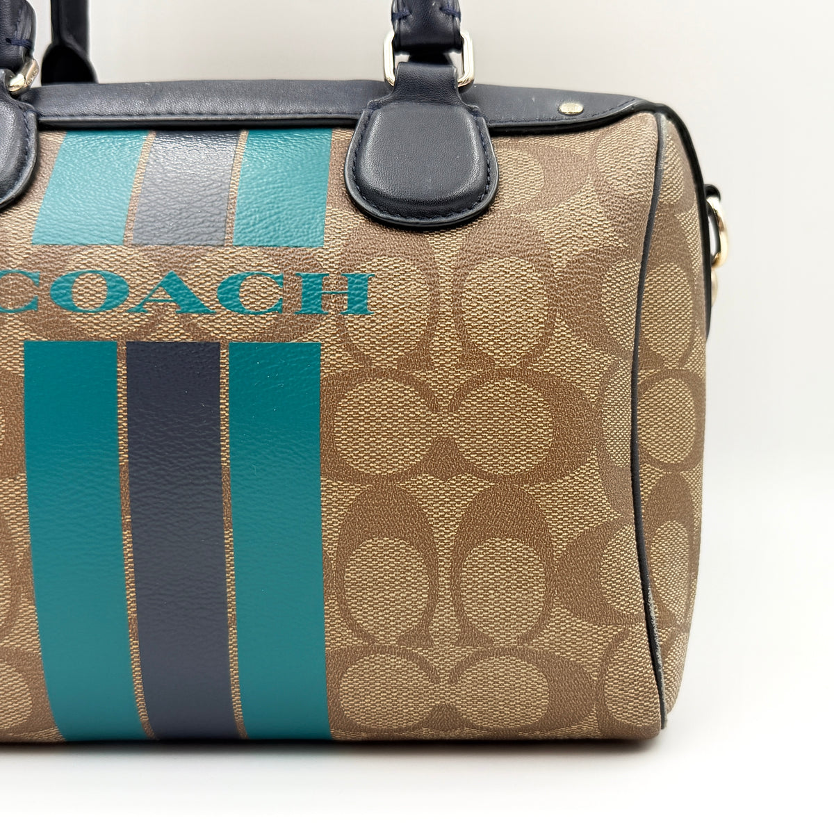 Coach Signature Mini Bennett Boston Bag in monogram canvas with navy and teal varsity stripes and dark navy leather trim.