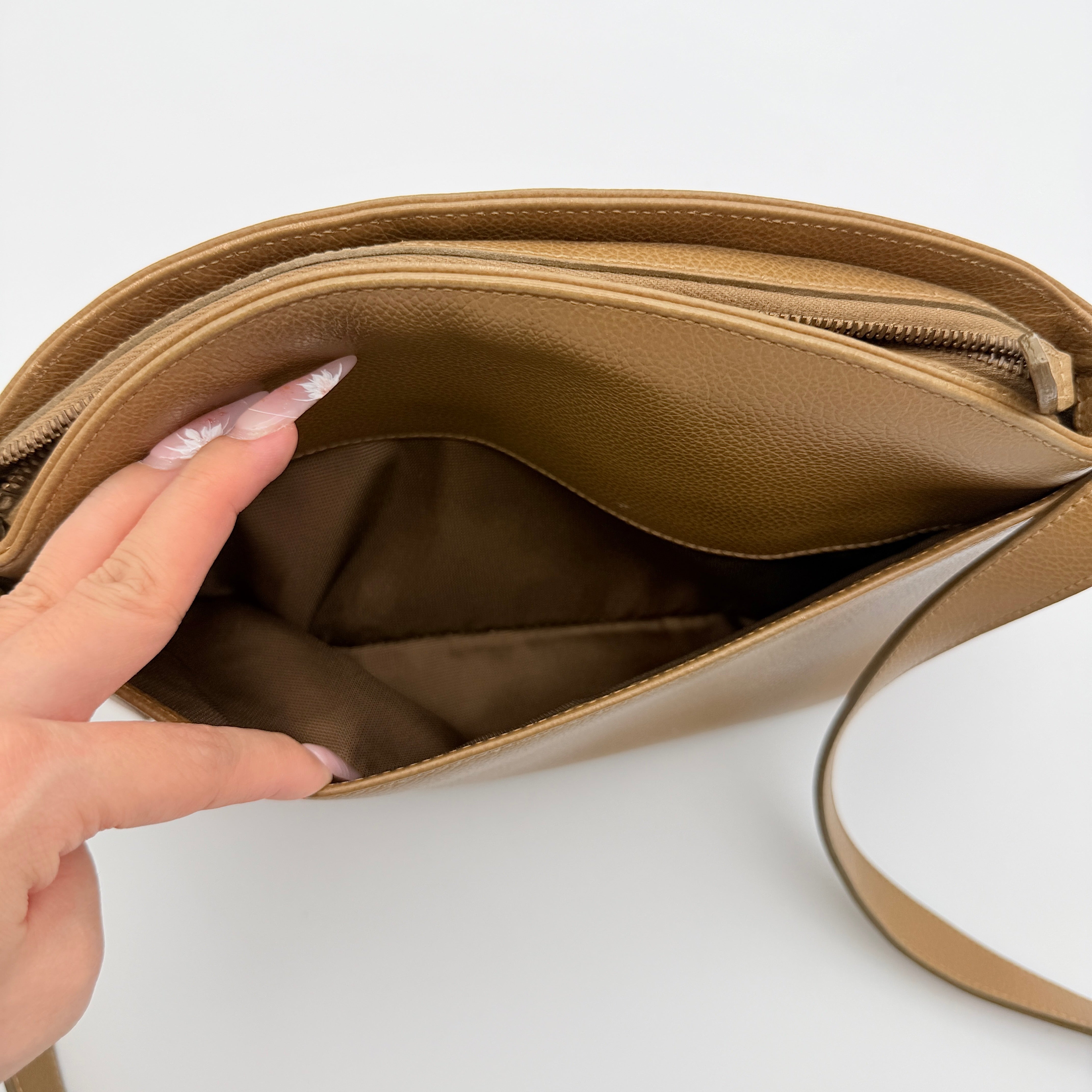 Coach tan leather crossbody bag with gold-tone hardware and adjustable strap, photographed on a white background.