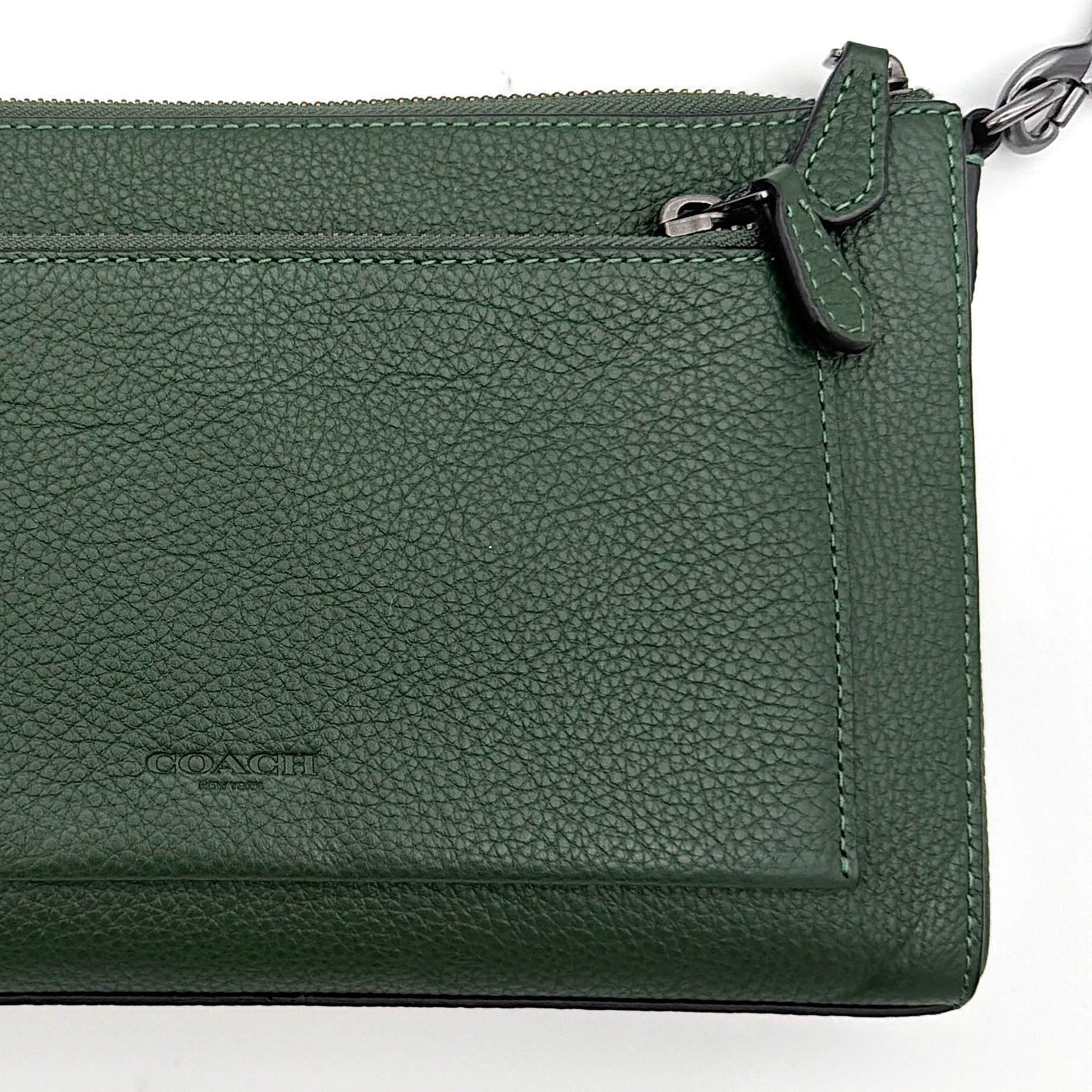 Coach Holden Crossbody bag in dark green pebbled leather with adjustable black webbing strap, displayed against a white background.