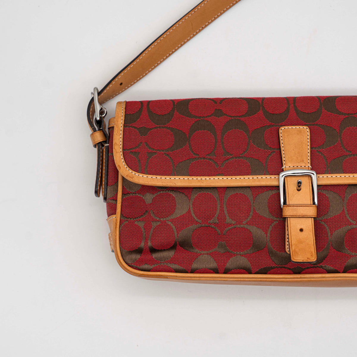 Coach Signature Soho Buckle Baguette in red and tan canvas with leather trim and a silver buckle, shown on a white background.
