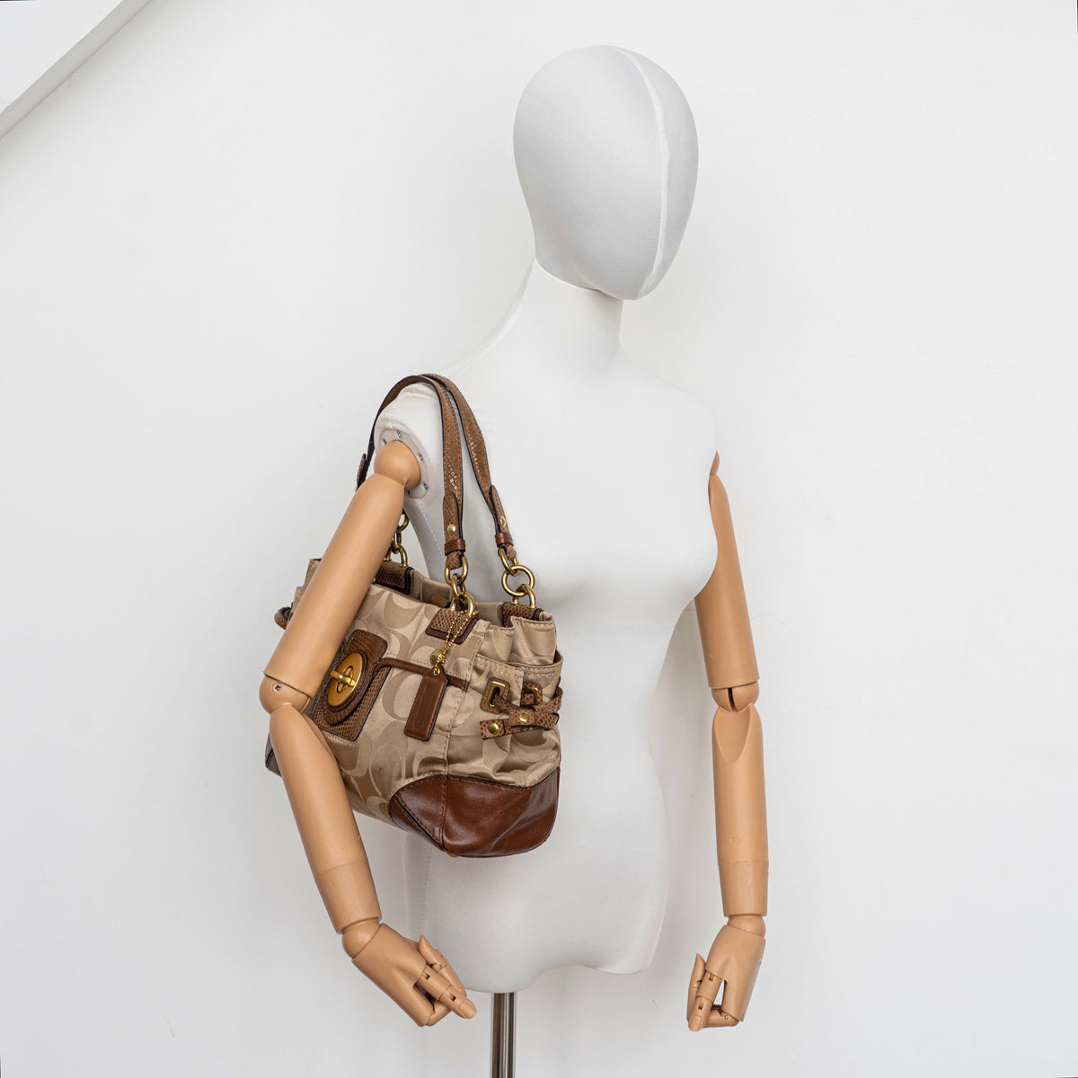 Coach Signature Peyton Shoulder Bag in brown sateen and leather with gold-tone hardware and turnlock pocket, photographed on a white background.