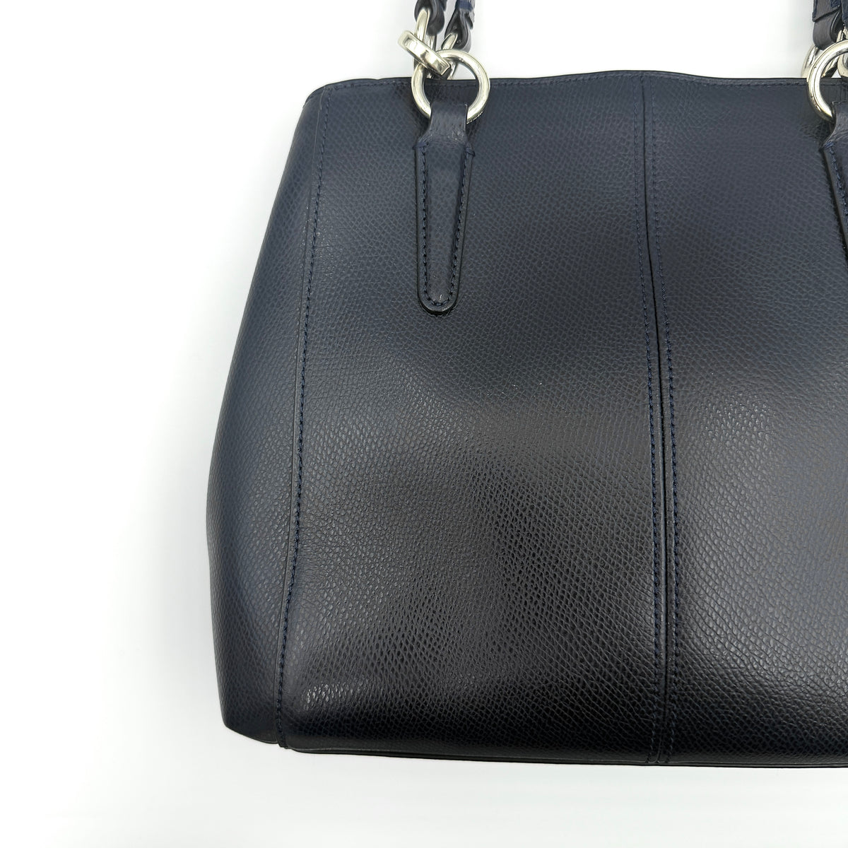 Coach Minetta Satchel in navy blue grained leather with dual handles and detachable shoulder strap displayed on a white background.