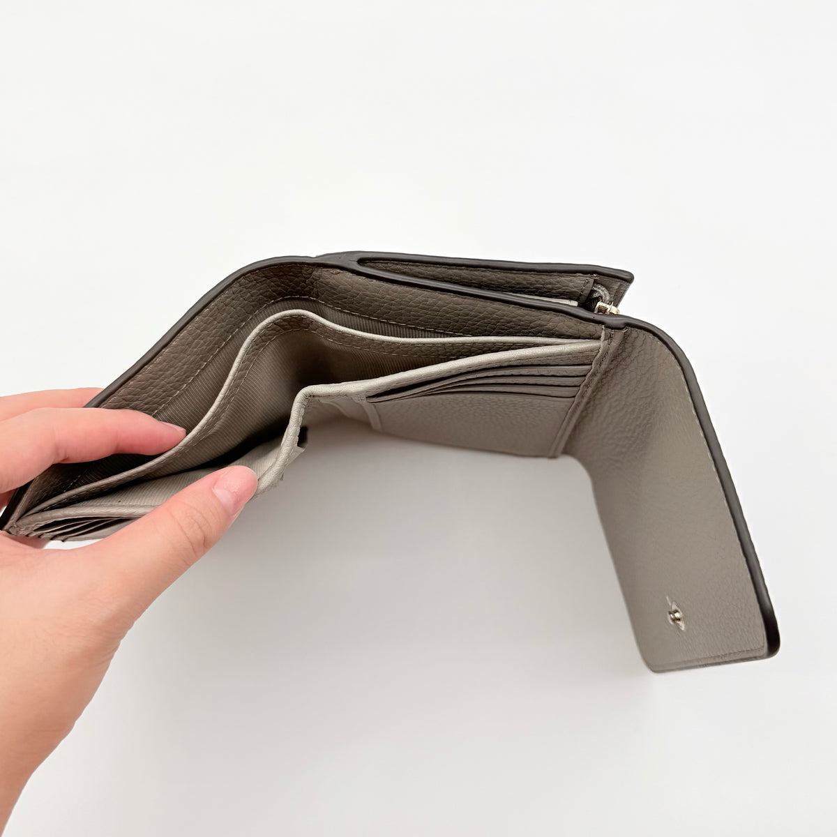 Furla Dafne Trifold Wallet in grey pebbled leather with gold-tone hardware and trifold interior, shown with original dust bag.