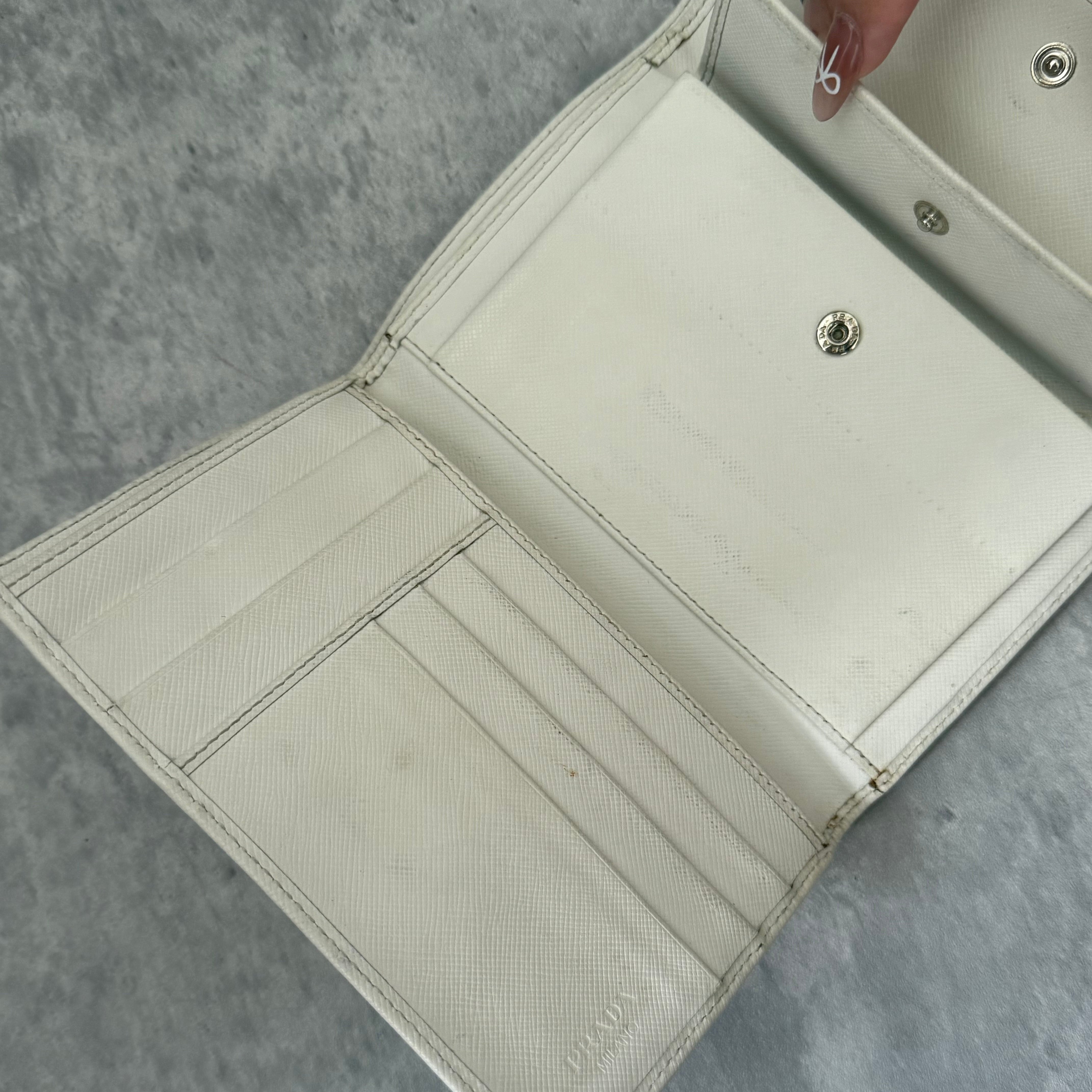 Pre-loved Prada Tessuto Nero leather trifold wallet with triangle logo plate in off-white, featuring card slots and a snap closure.