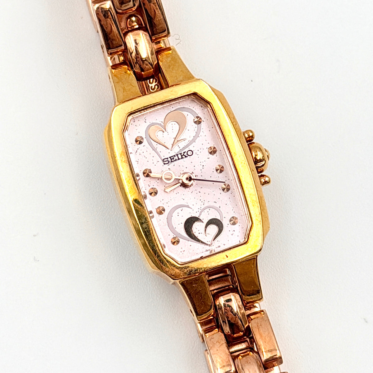 Front view of the Seiko Tisse Nozomi Special Edition watch with a pink heart motif dial and two-tone gold and rose gold bracelet.