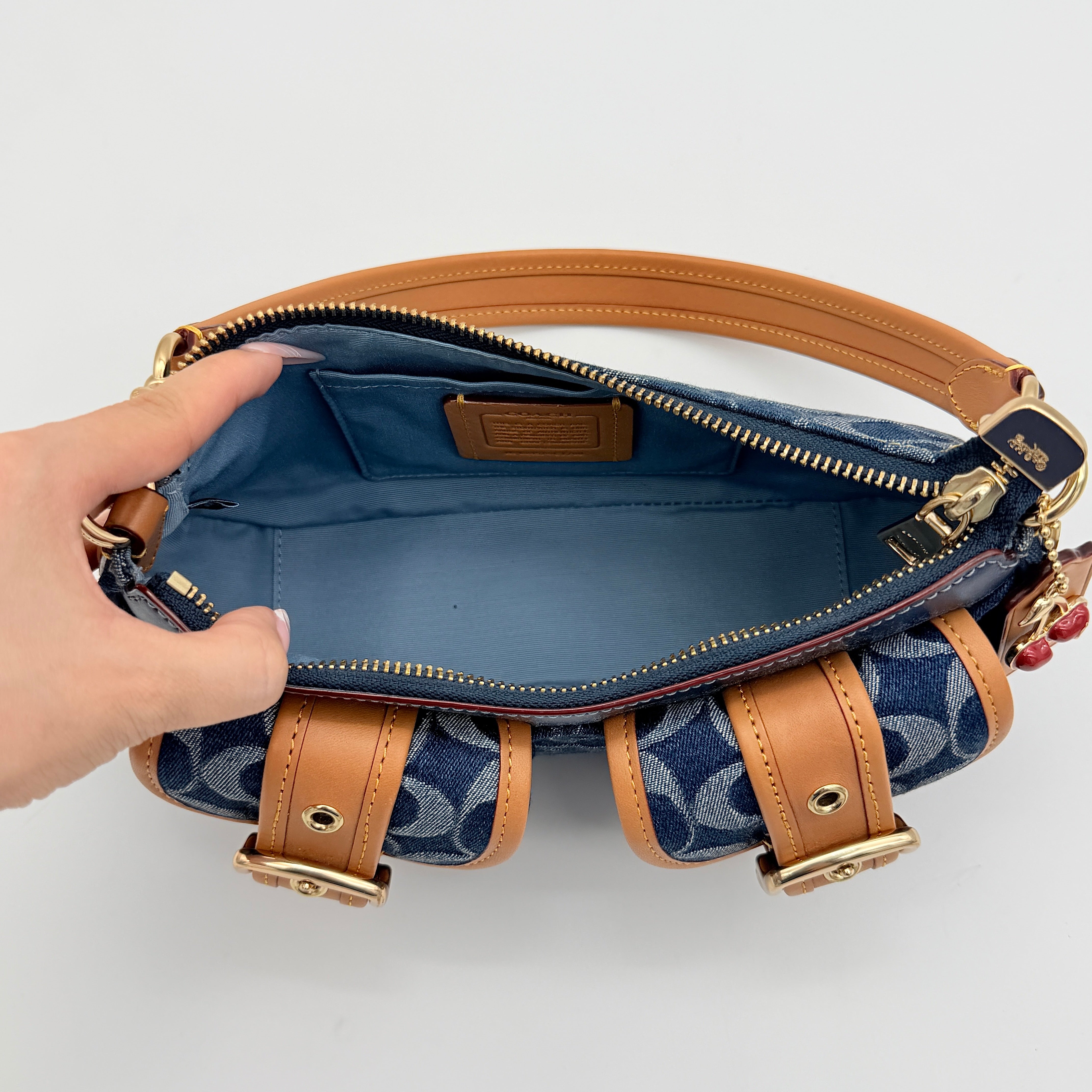 Coach Signature Ashton shoulder bag in blue denim and tan leather with gold hardware, shown with removable strap and dust bag.