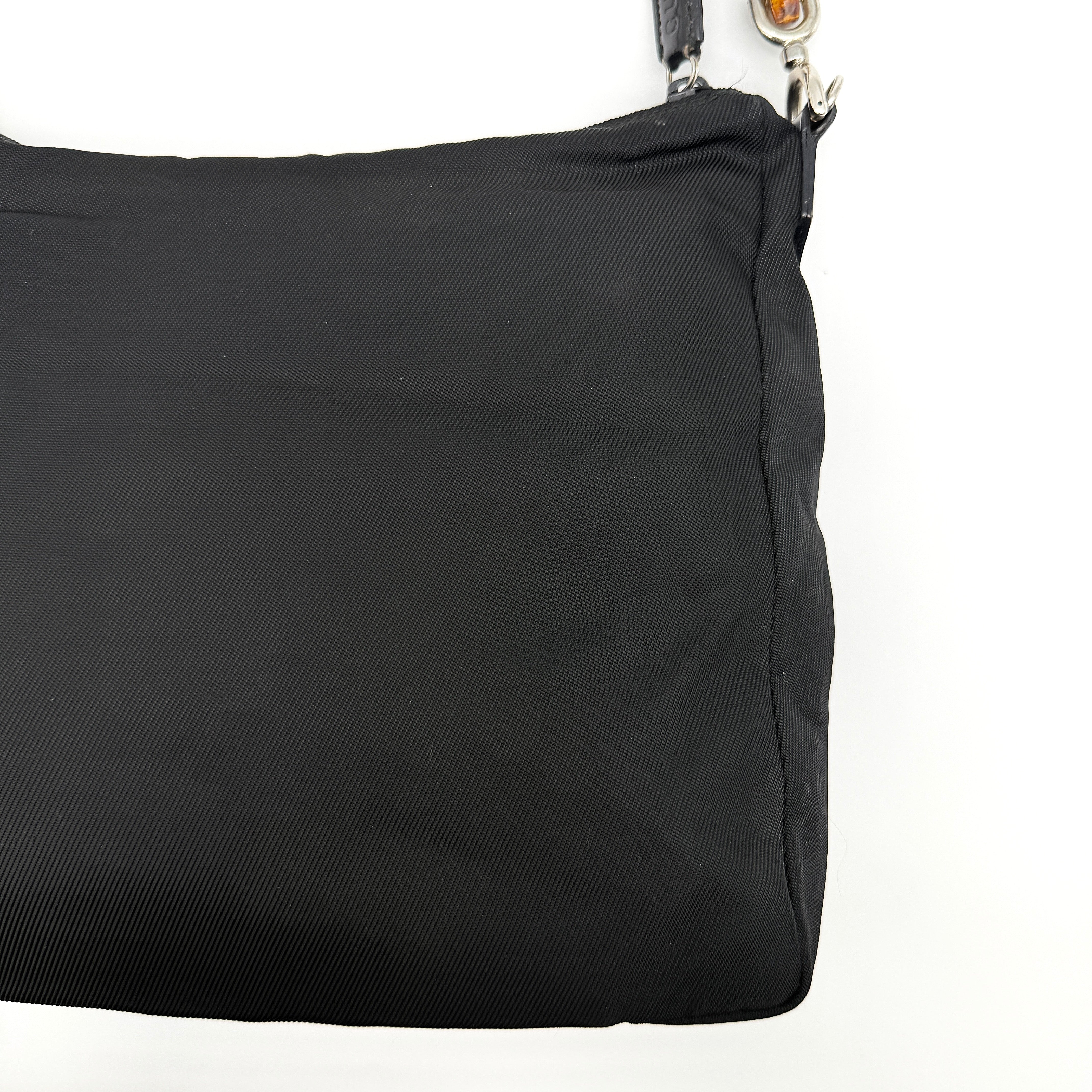 Gucci nylon shoulder bag in black with bamboo handle, shown against a white background.