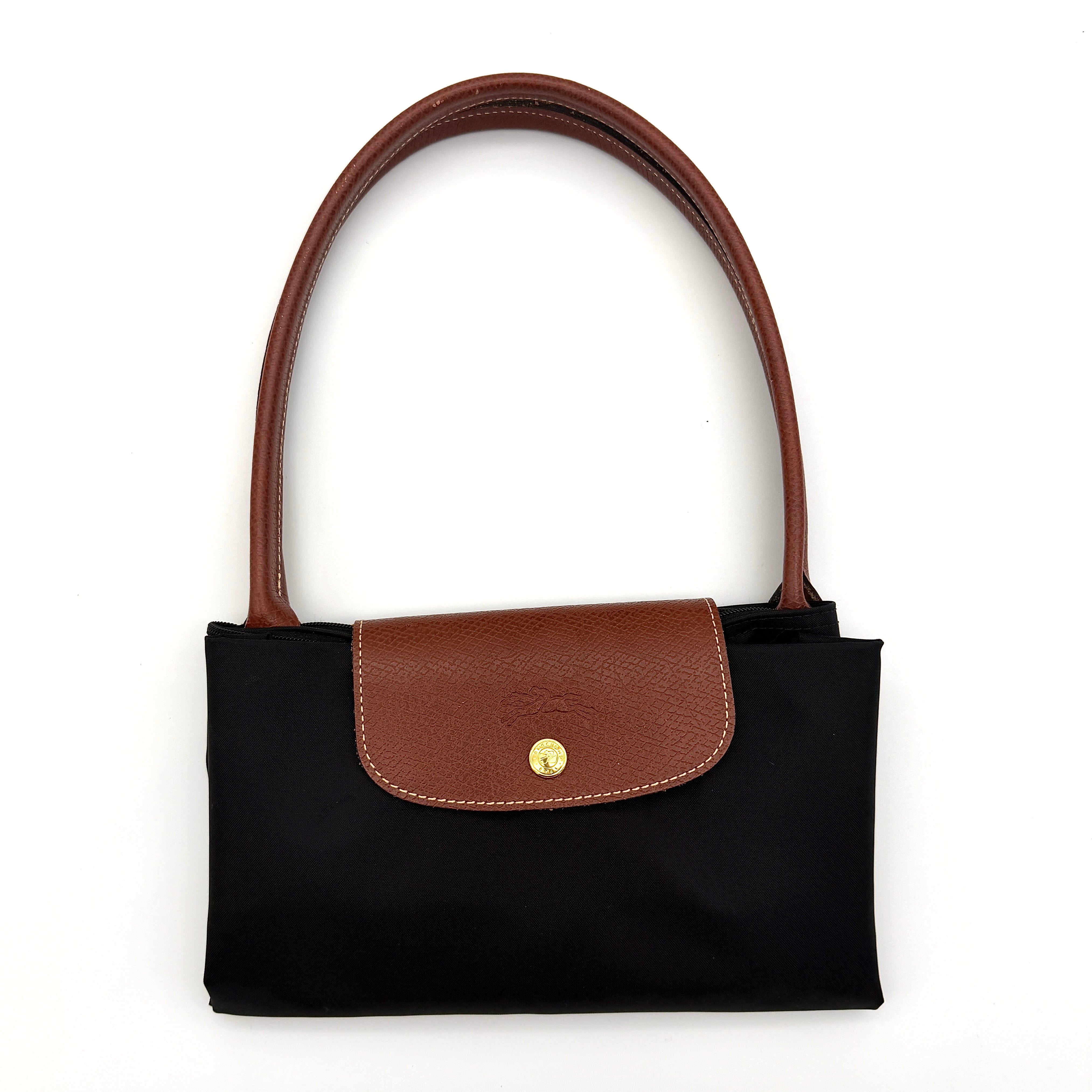 Longchamp Le Pliage Original Tote Bag in black with brown leather handles and flap, photographed against a white background.