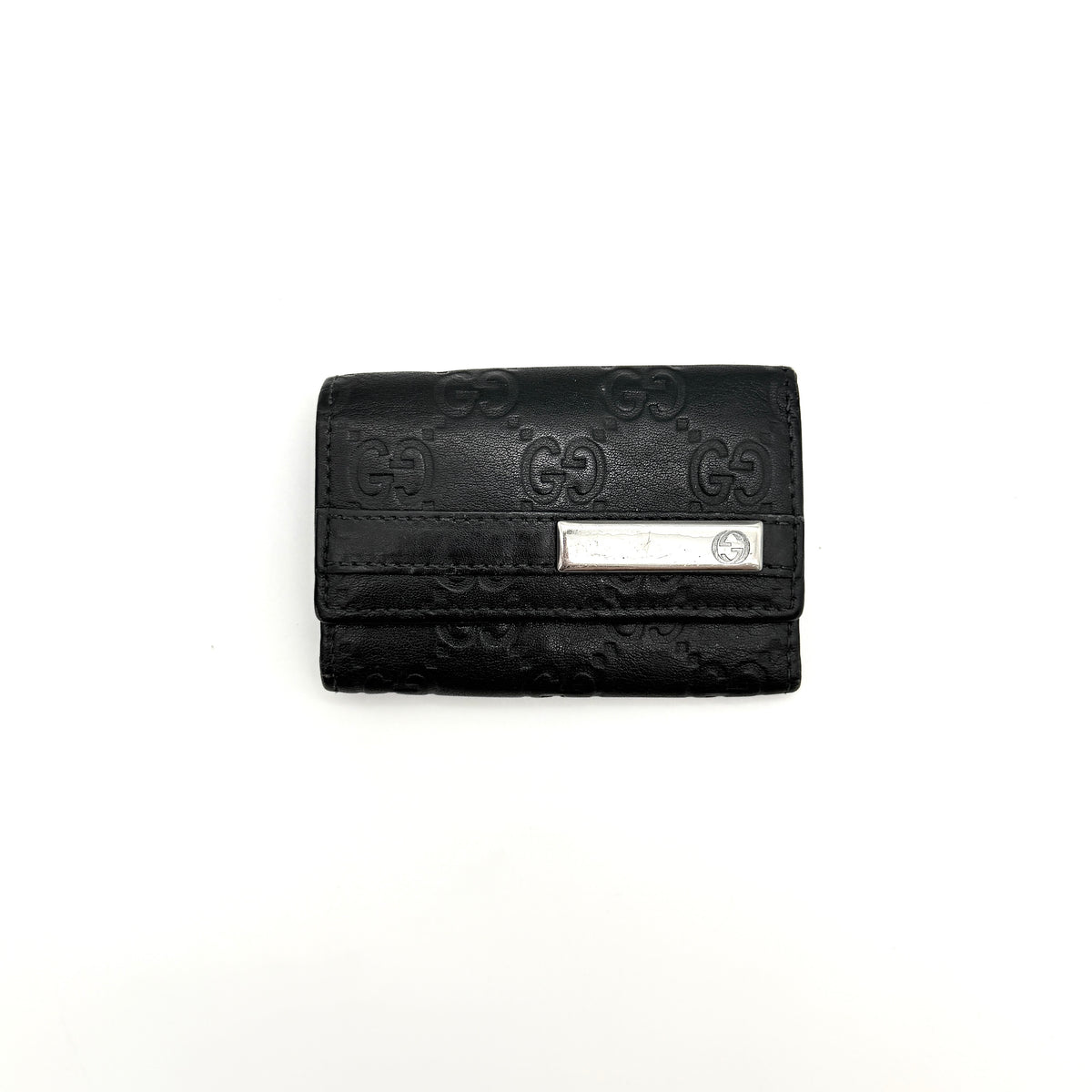 Gucci Guccissima GG Monogram black leather key case with silver-tone hardware, shown closed against a white background.