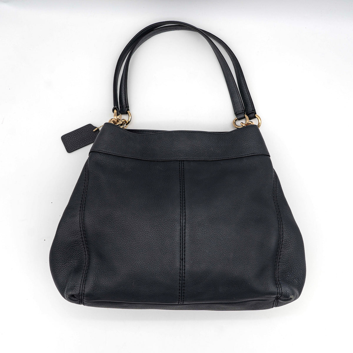 Coach Lexy Shoulder Bag in black pebbled leather with gold-tone hardware and double handles, styled against a white background.