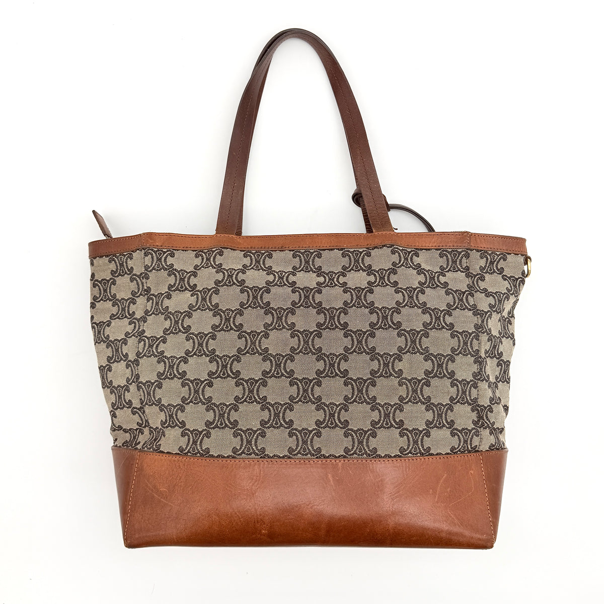 Celine Triomphe Macadam Canvas Tote Bag in beige and brown with leather trim and top handles, styled against a white background.