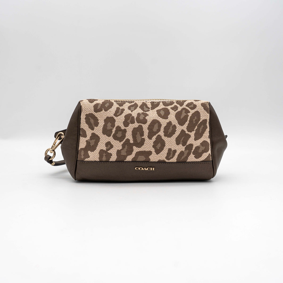 Coach cosmetic pouch in brown and beige leopard print canvas with chocolate leather trim and gold hardware, shown with wrist strap.