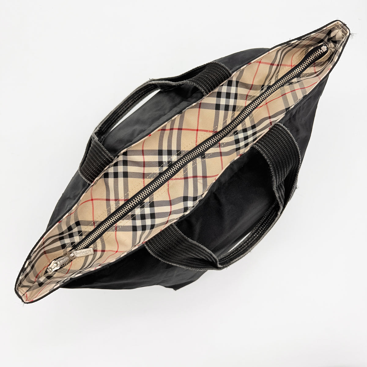Burberry Blue Label Nova Check tote bag in black nylon with beige checked base and webbed handles, shown on white background.