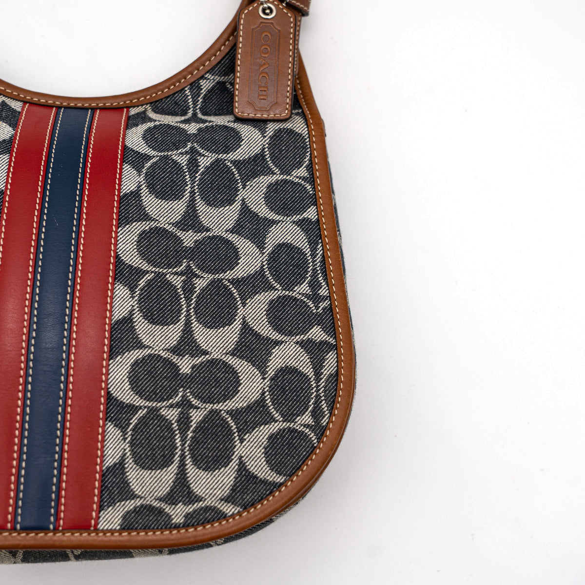 Coach signature denim hobo crossbody bag with red and blue stripe, brown leather trim, and an adjustable strap.