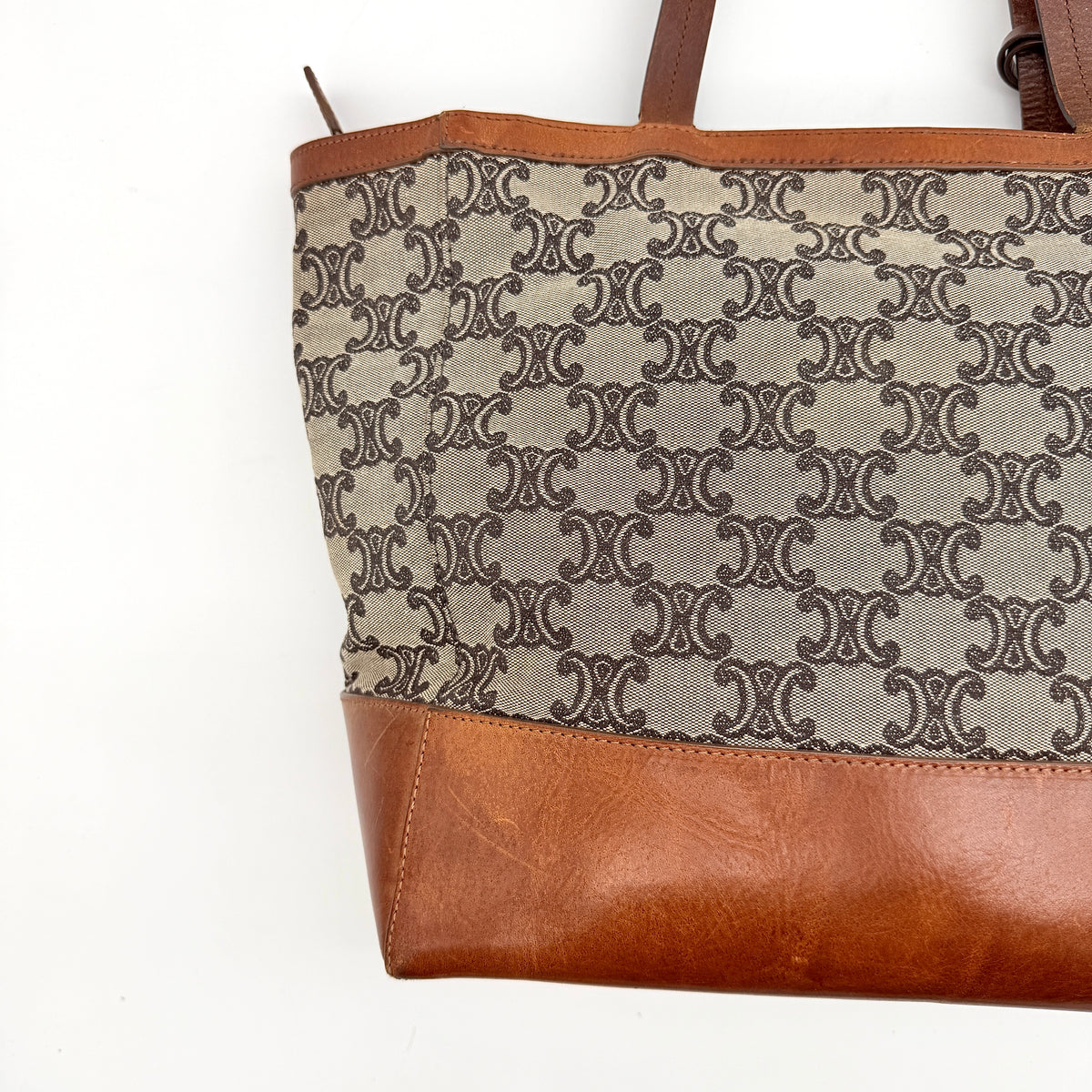 Celine Triomphe Macadam Canvas Tote Bag in beige and brown with leather trim and top handles, styled against a white background.