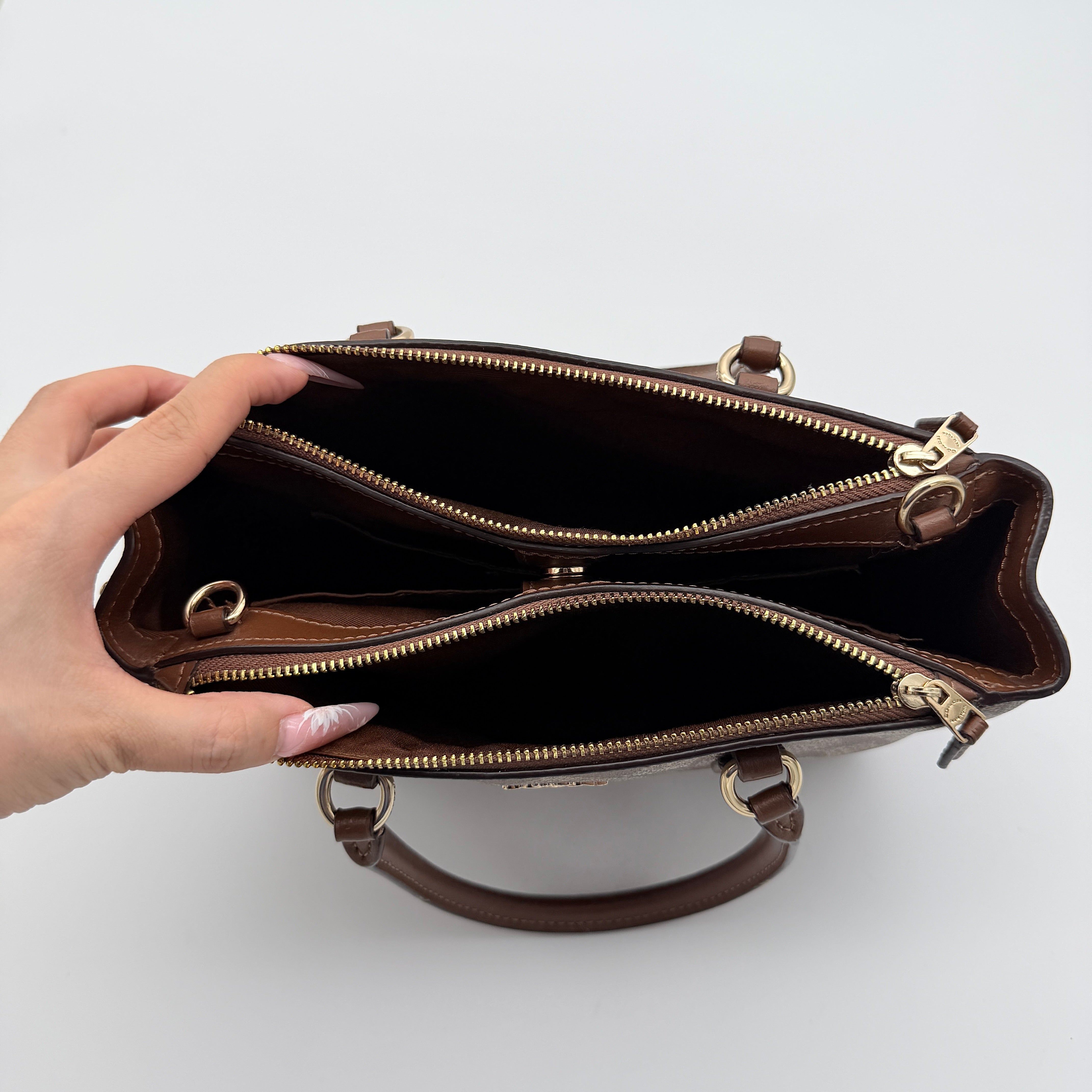 Coach Christie Carryall in beige and brown canvas with gold hardware and detachable strap, photographed in a studio setting.