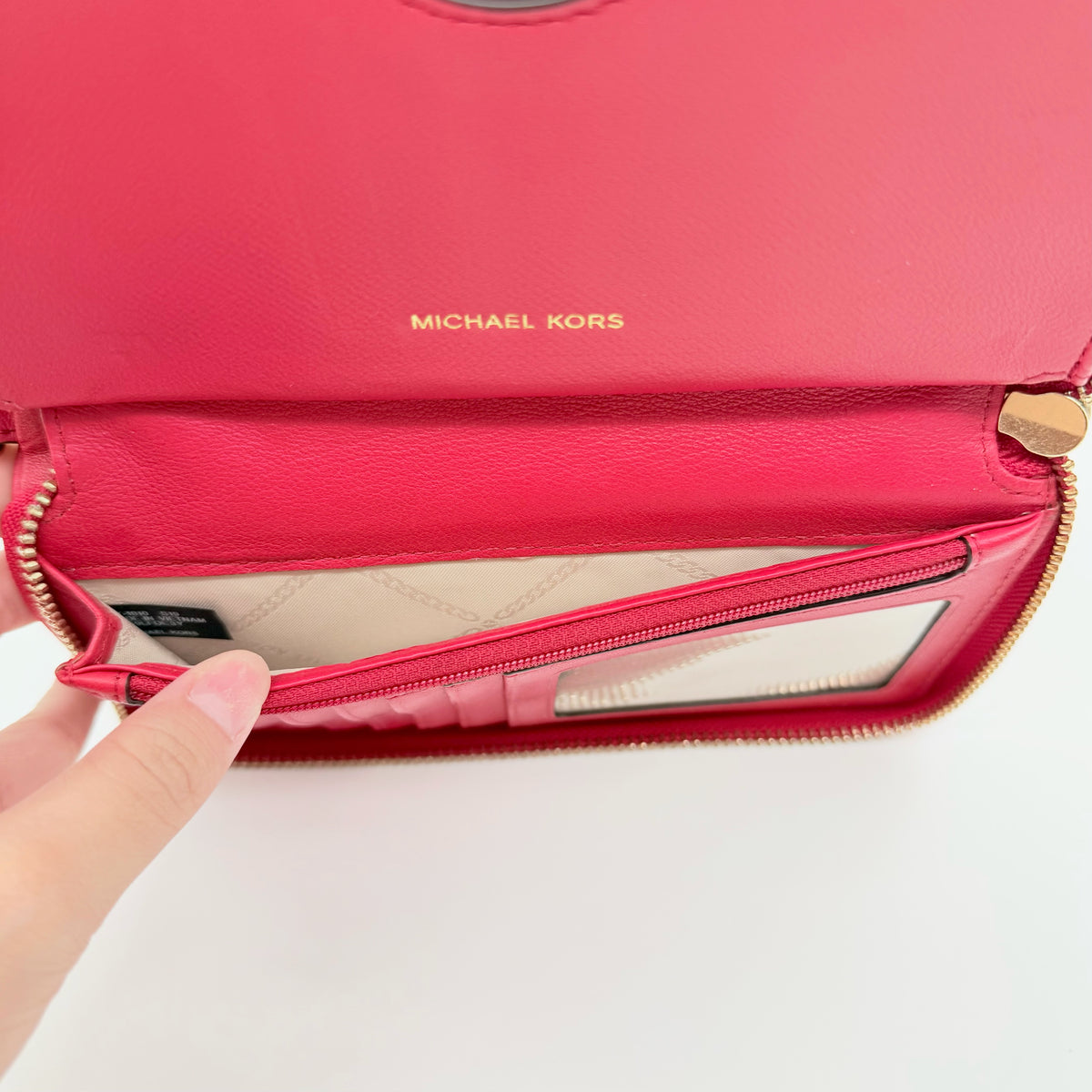 Front view of the Michael Kors red quilted large wallet with gold zip and MK monogram stitching.