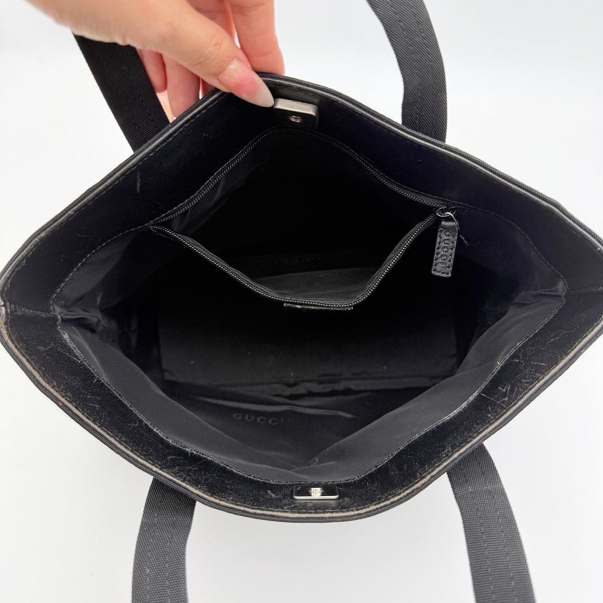 Front view of the Gucci black nylon tote with dual zip pockets and leather top handles.