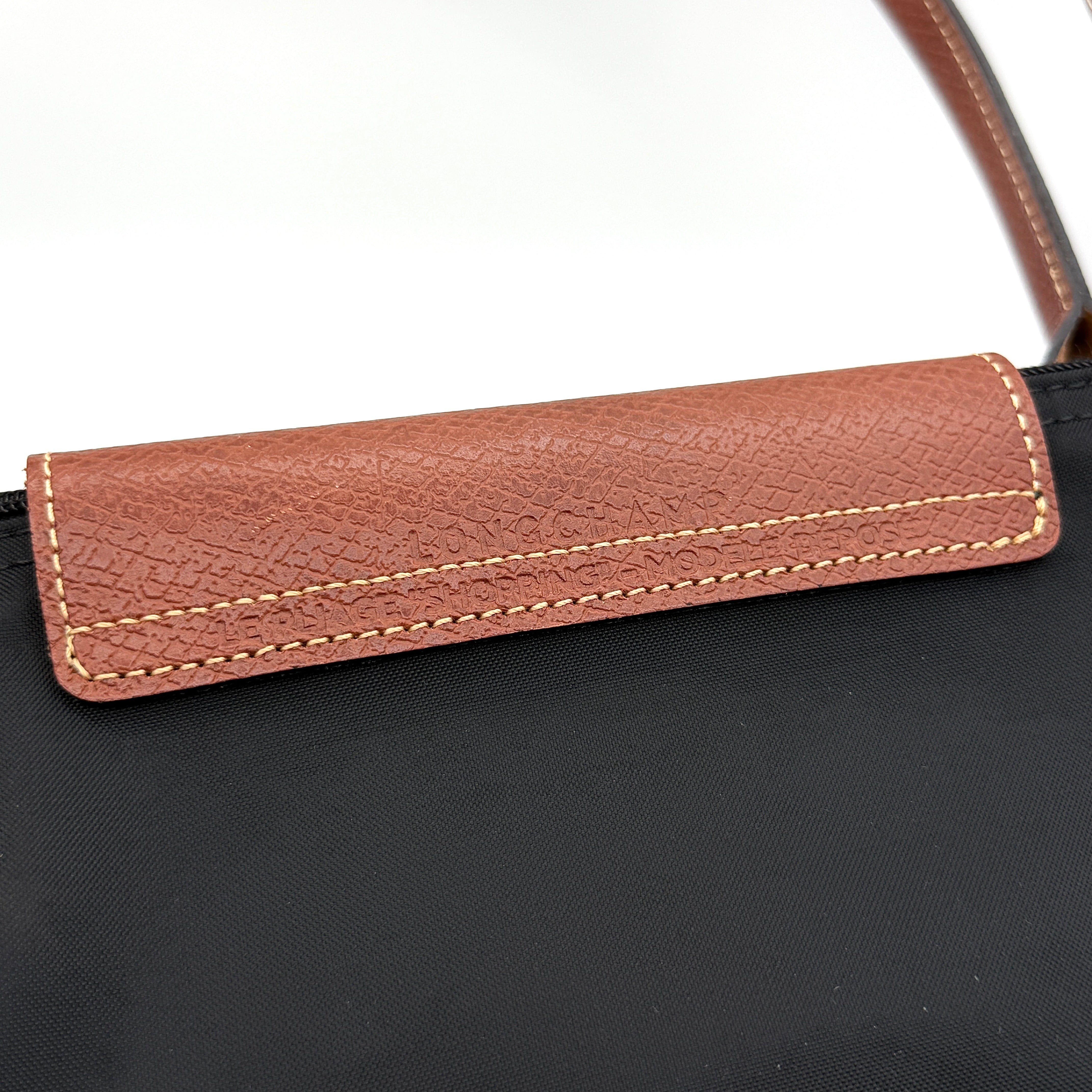 Longchamp Le Pliage Original Tote Bag in black with brown leather handles and flap, photographed against a white background.