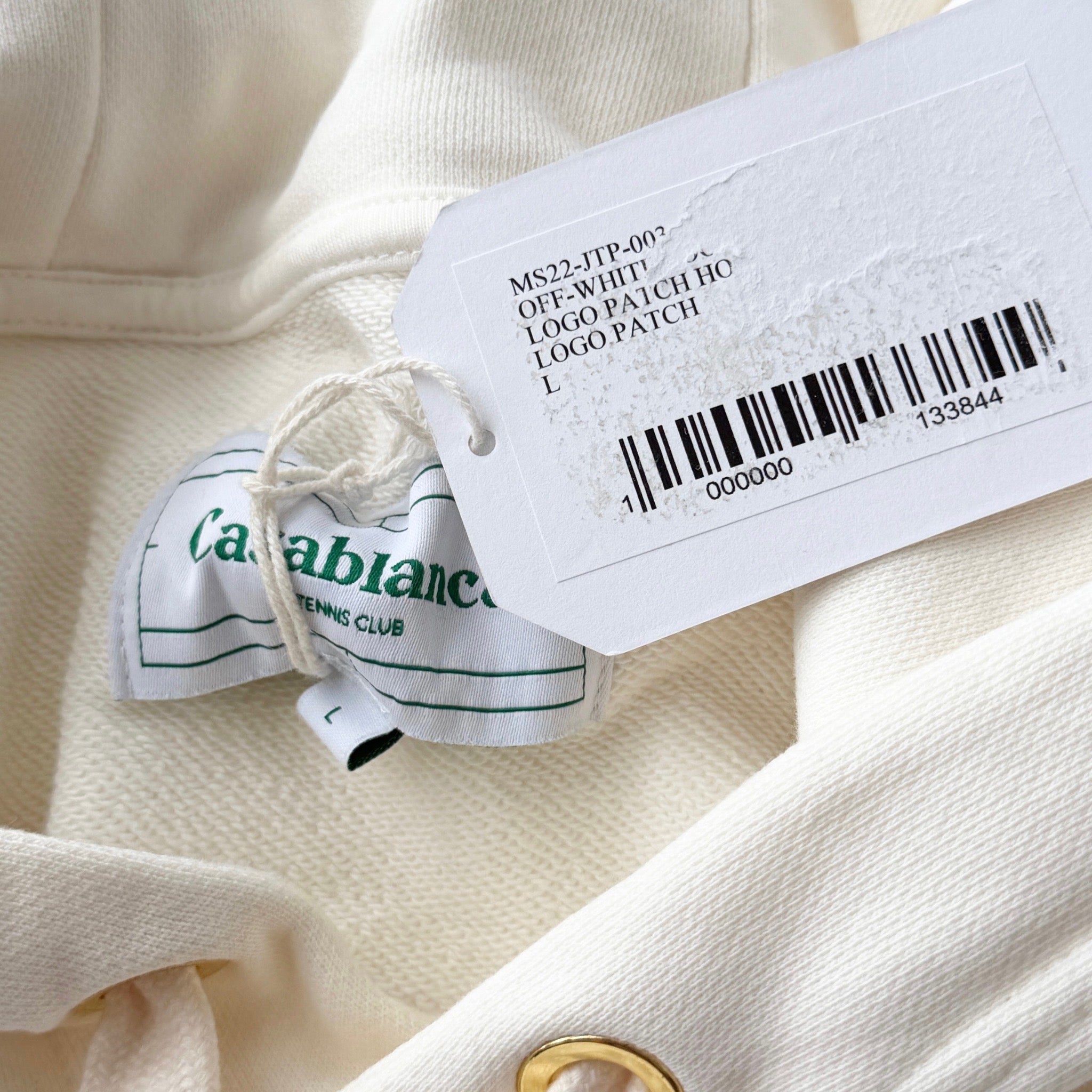 Casablanca off-white hoodie with a red logo patch and kangaroo pocket, laid flat and showing the front view.