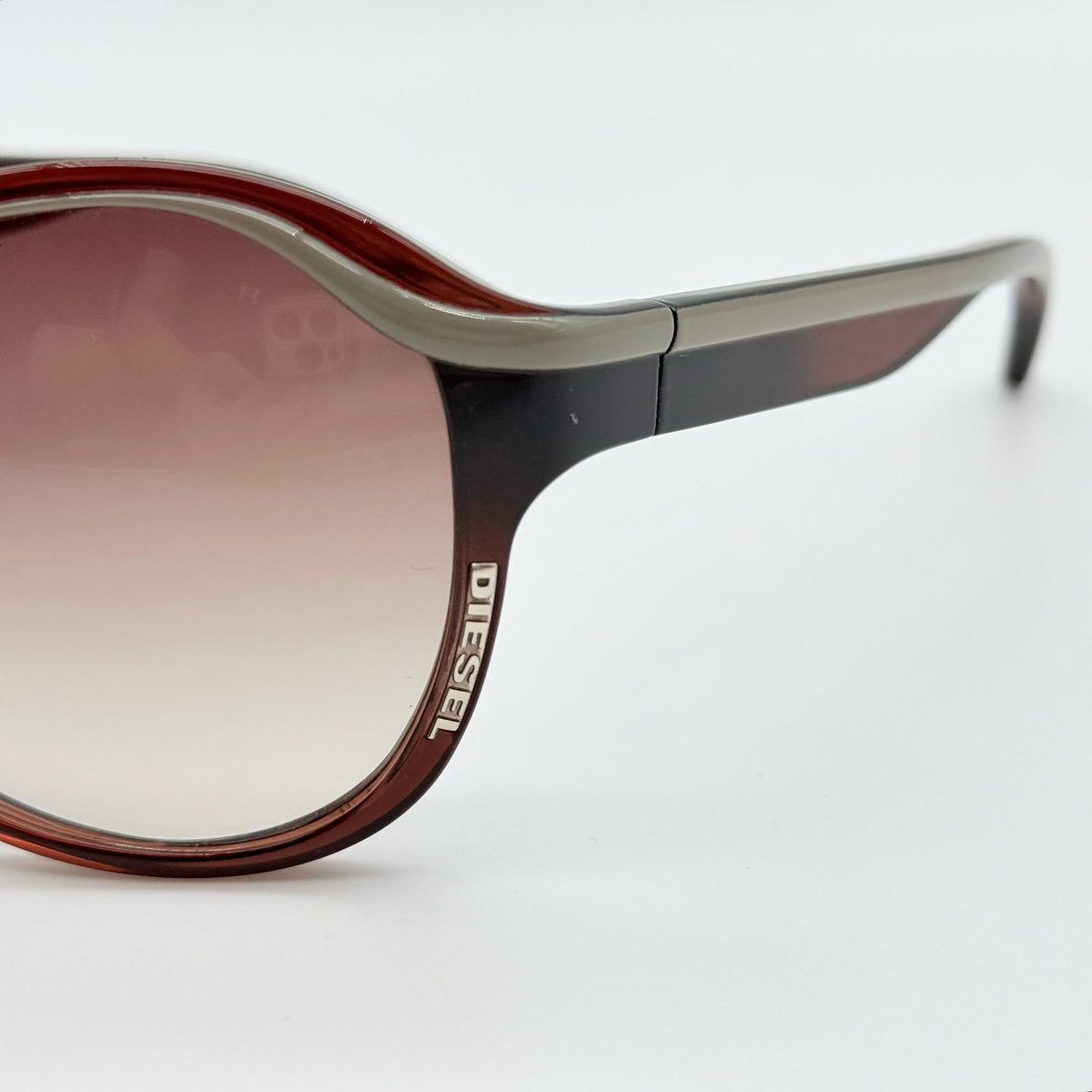 Diesel DS0094 sunglasses in gradient brown with oversized round lenses, shown with branded case and cleaning cloth.