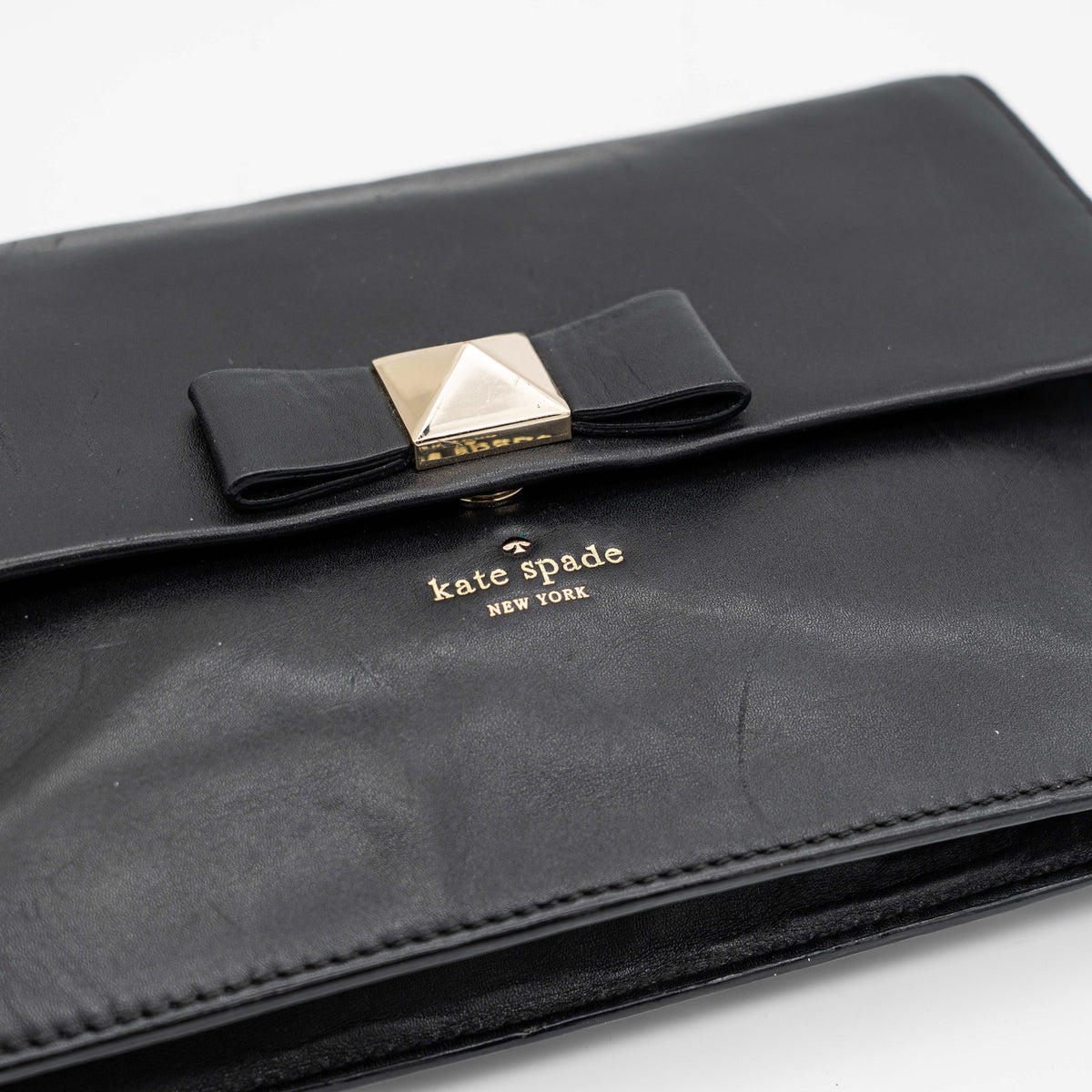Kate Spade New York black leather shoulder bag with gold chain strap and bow detail, displayed against a white background.