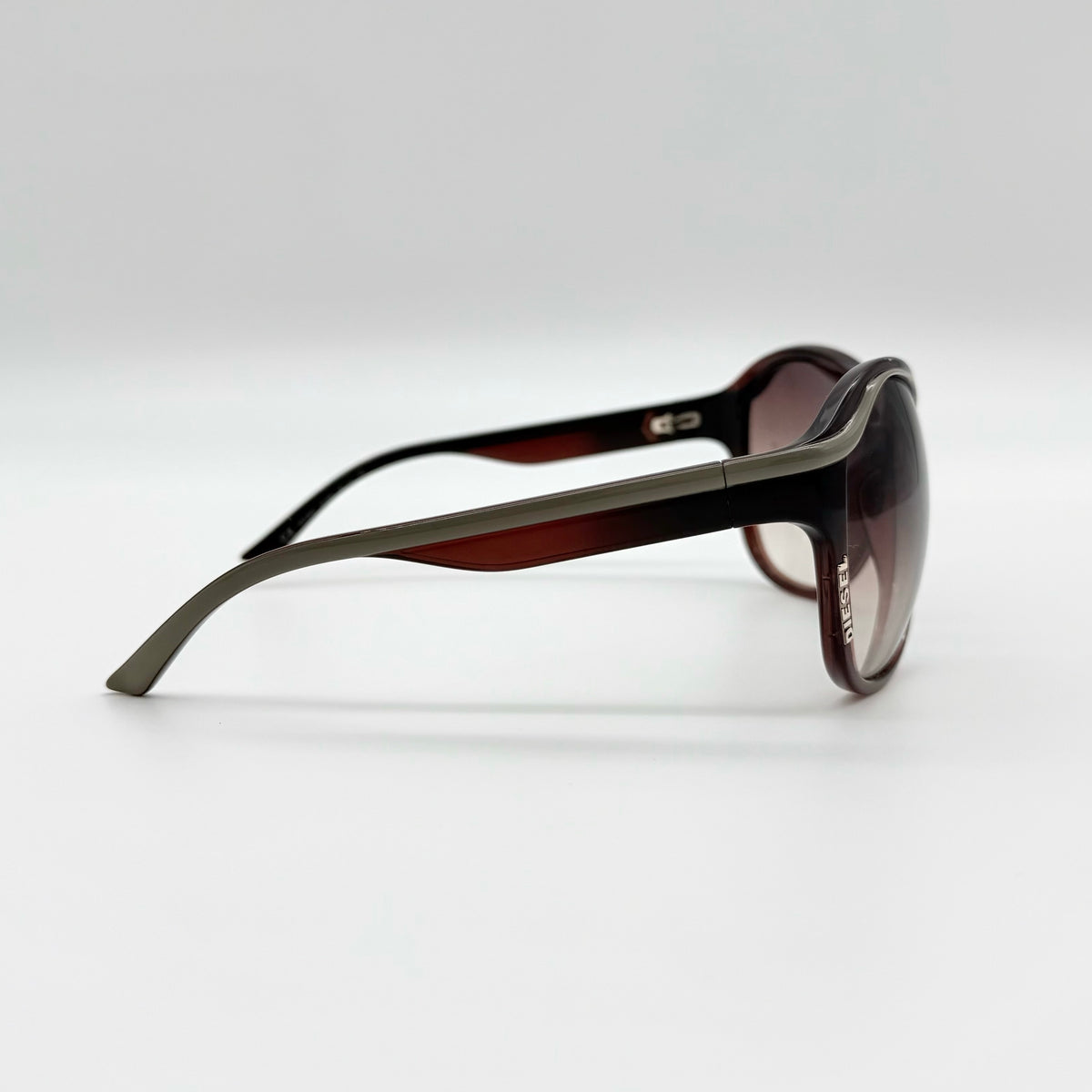 Diesel DS0094 sunglasses in gradient brown with oversized round lenses, shown with branded case and cleaning cloth.