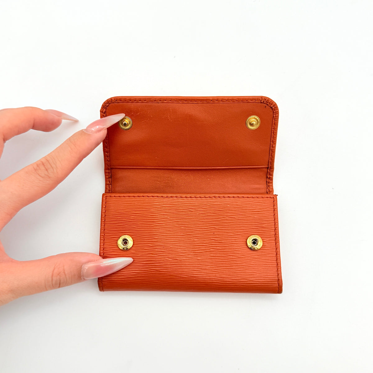 Prada Saffiano leather key case in orange with gold-toned hardware, Prada logo, and authenticity card displayed.