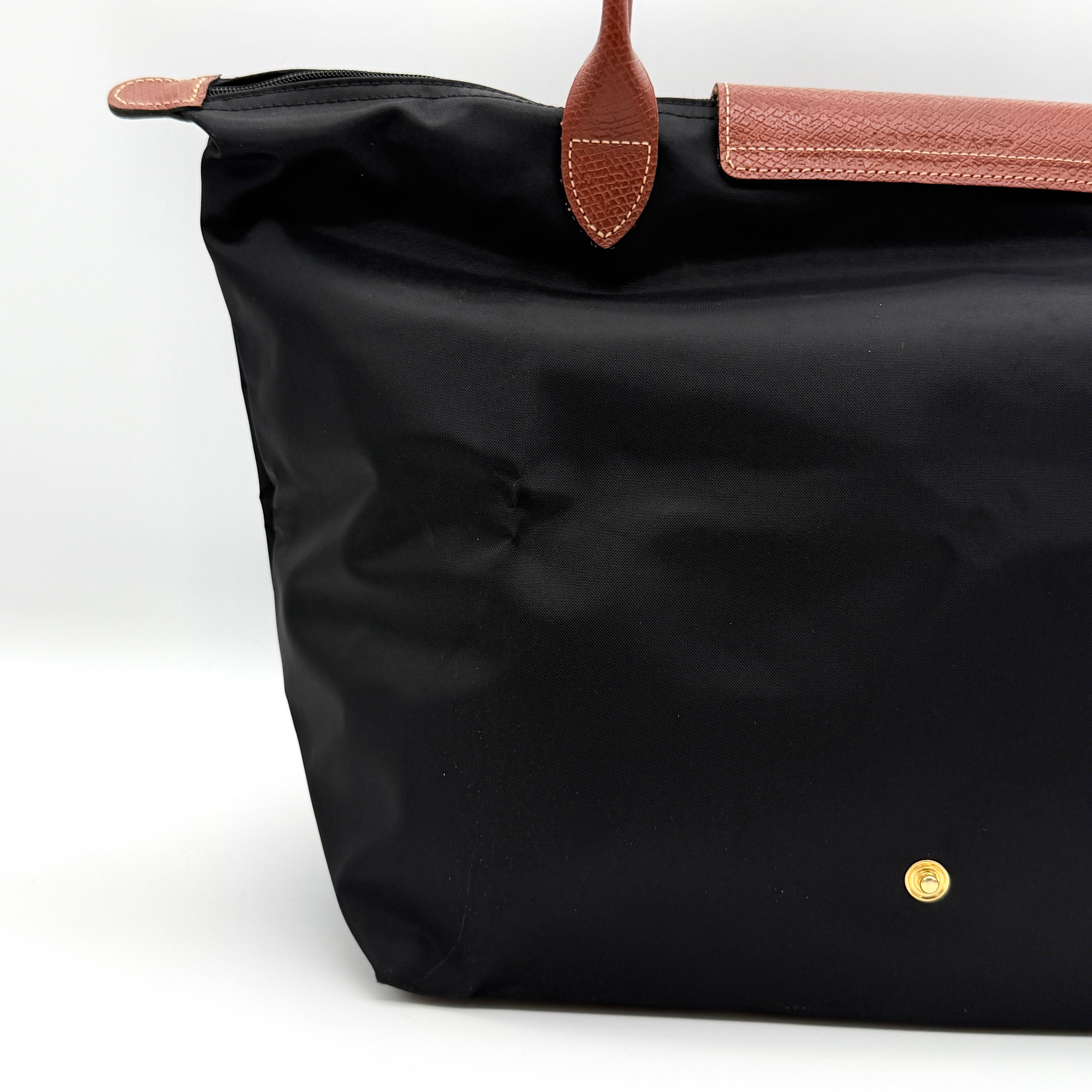 Longchamp Le Pliage Original Tote Bag in black with brown leather handles and flap, photographed against a white background.