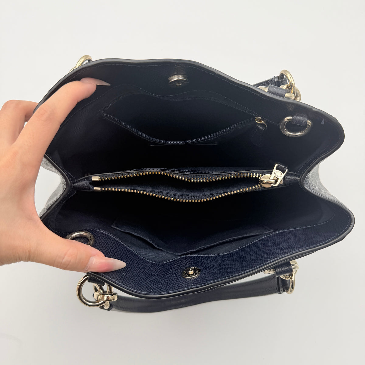 Coach Minetta Satchel in navy blue grained leather with dual handles and detachable shoulder strap displayed on a white background.